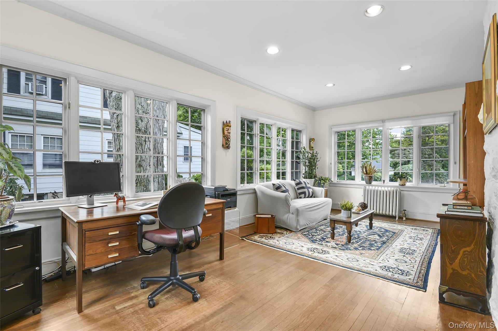Family room has 3 walls of windows, hardwood flooring and recessed lighting.
