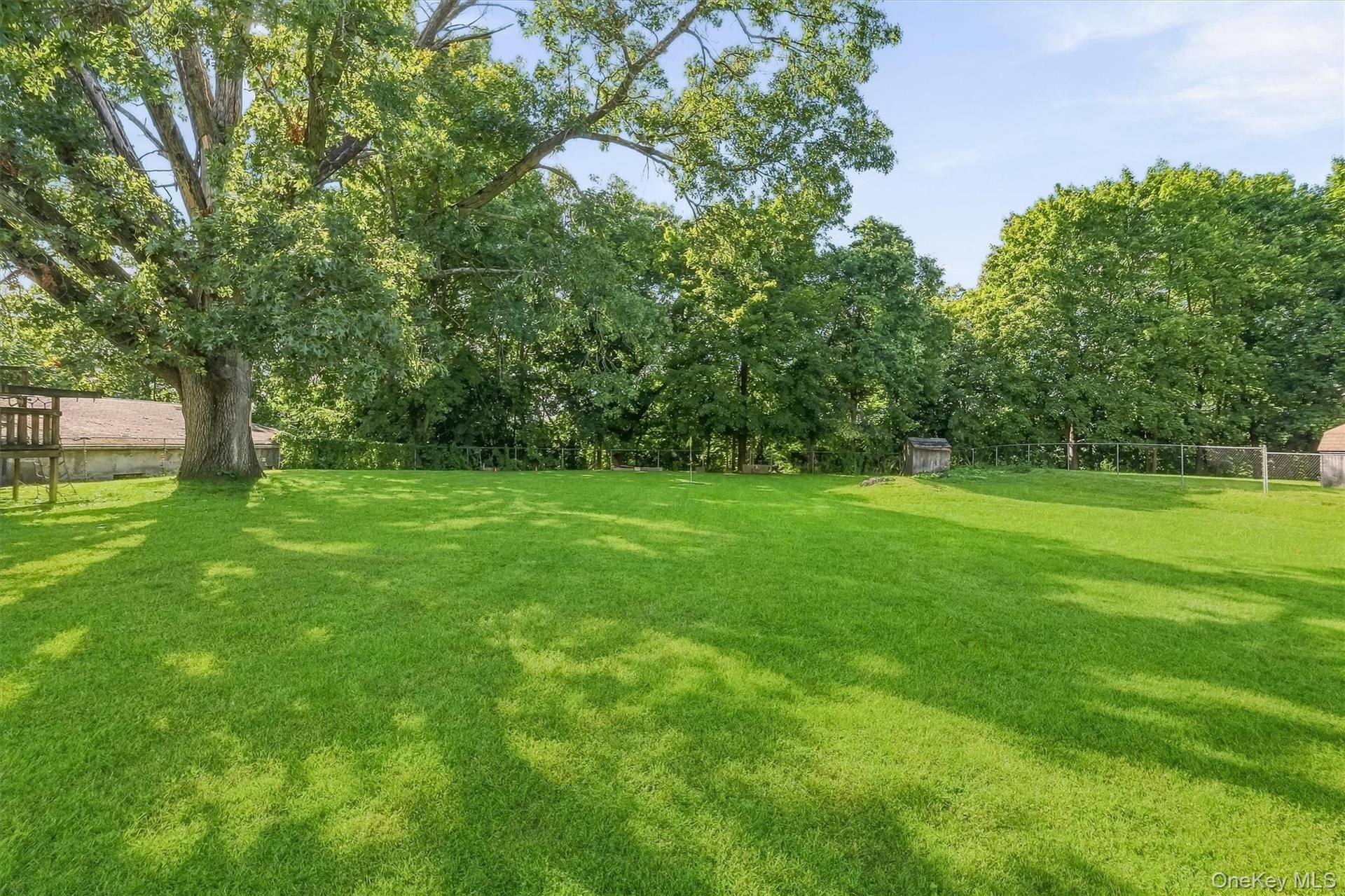 Expansive lawn with mature trees and perimeter fencing