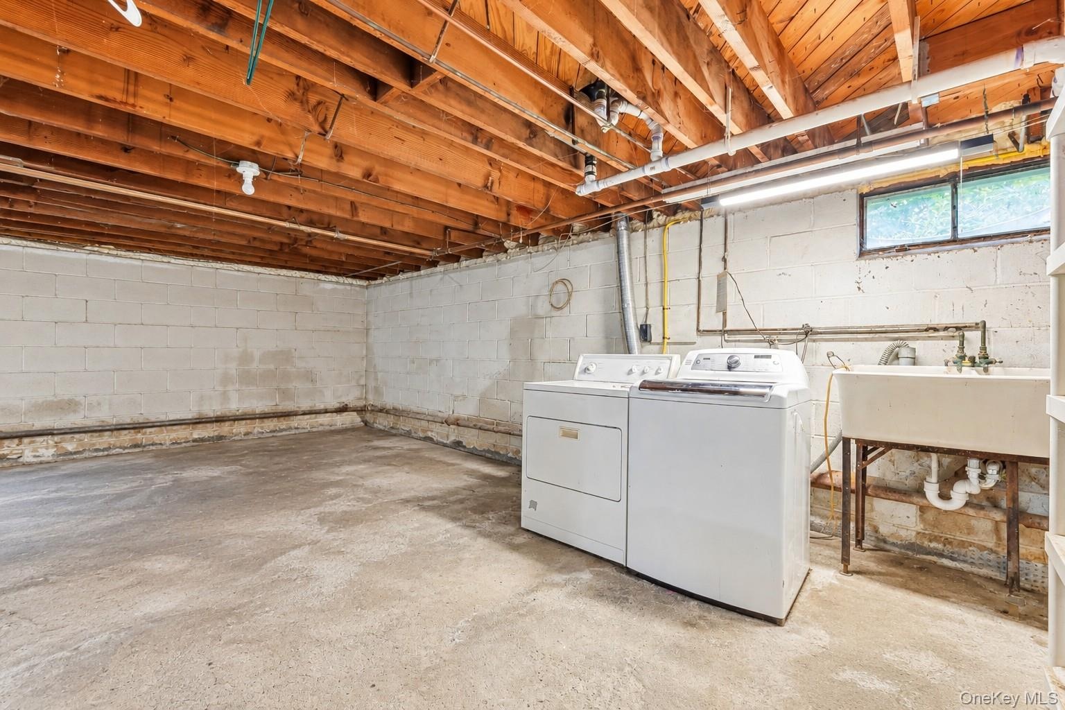 Laundry area featuring a utility sink, a window, and exposed wood beam ceiling