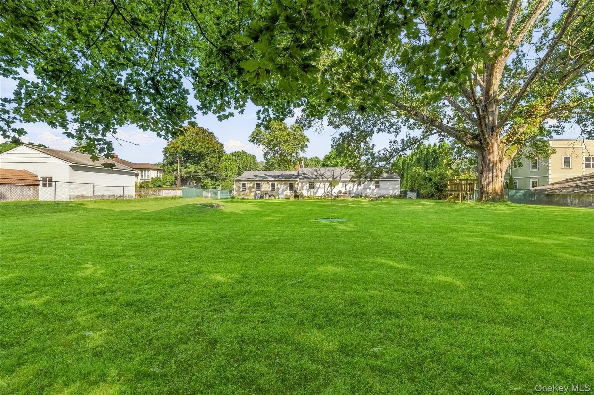 Expansive green lawn with mature trees and perimeter fencing
