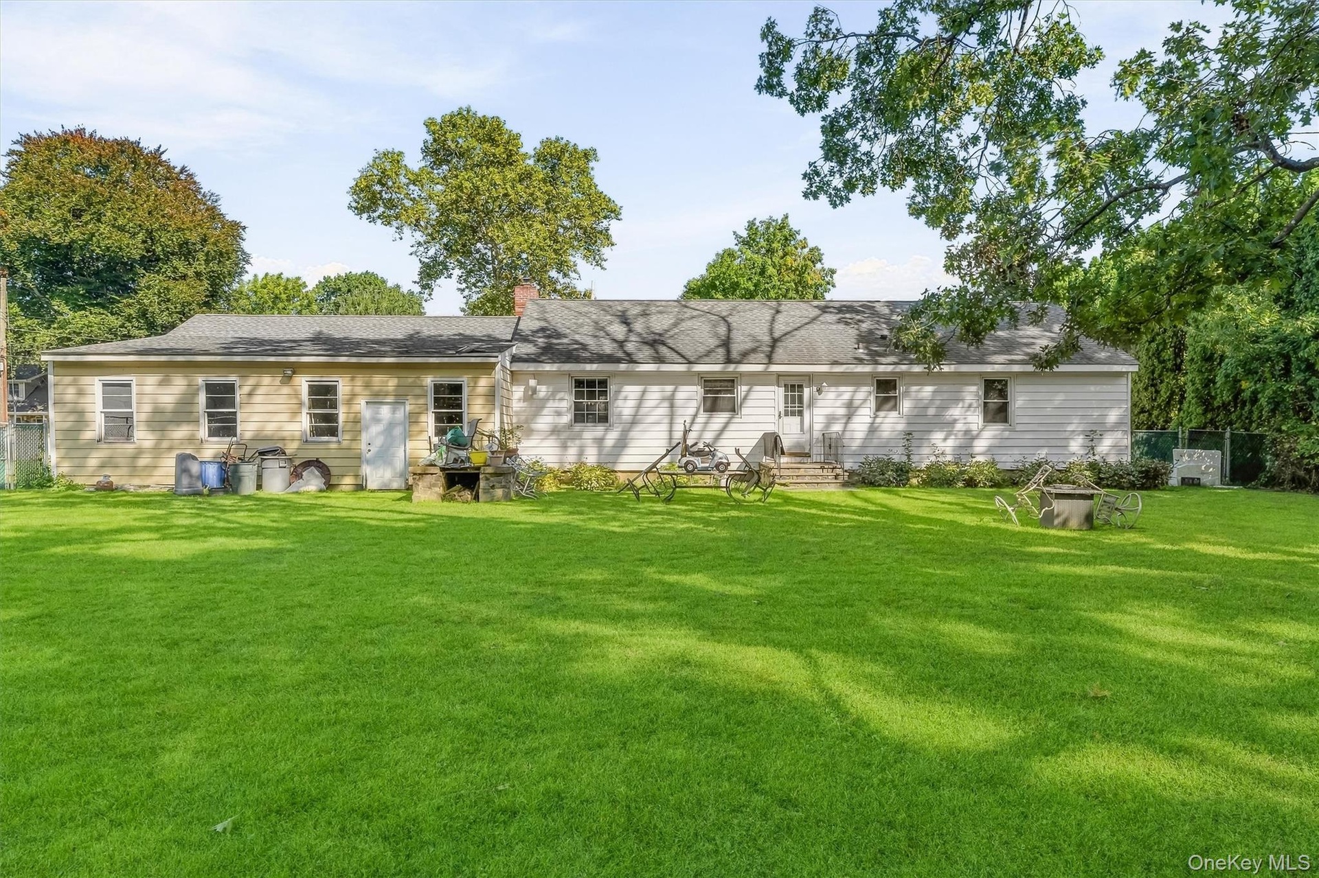 Expansive backyard featuring a manicured lawn, established trees, and two single-story structures with siding