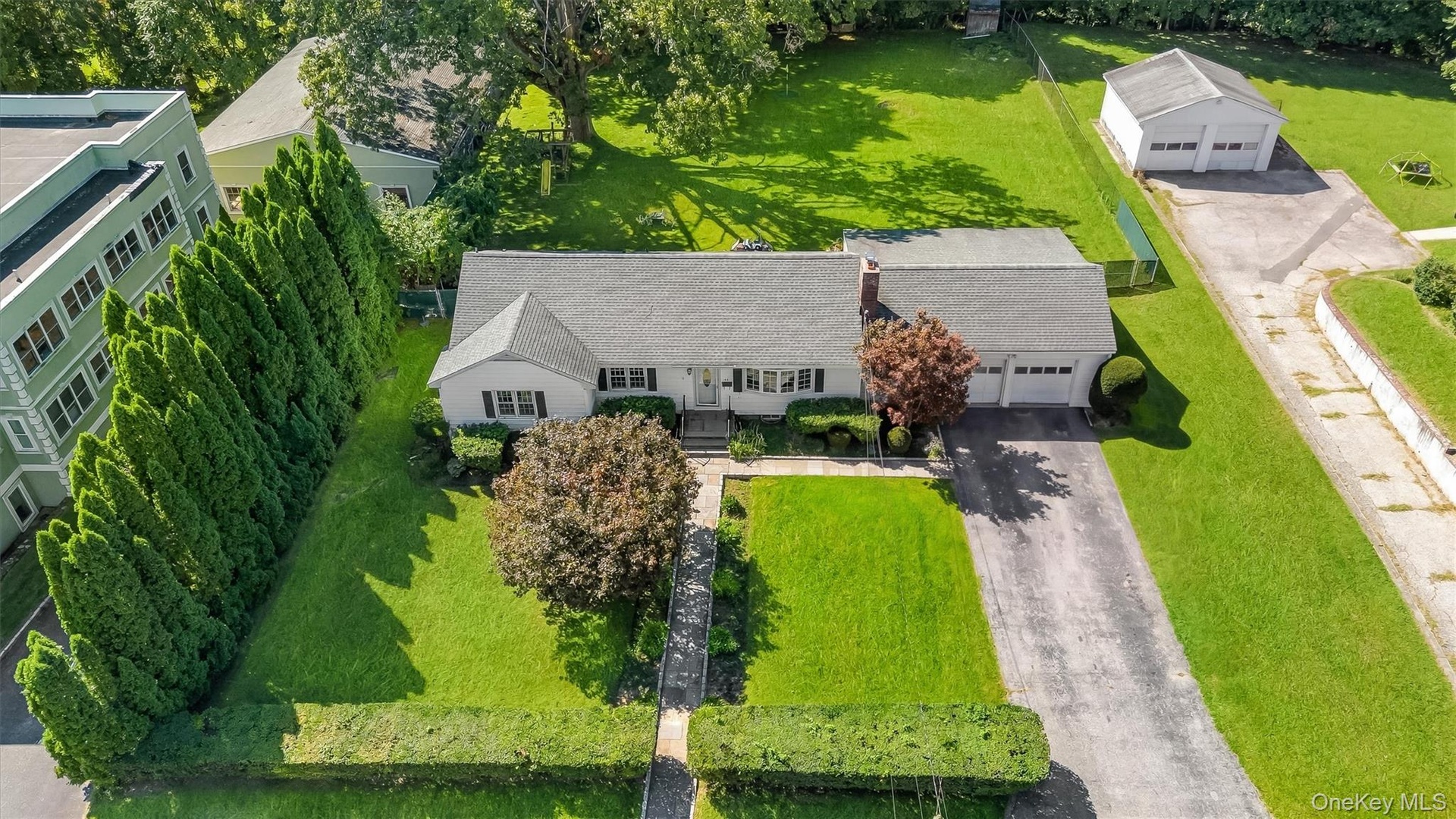 Single-story residence with a two-car garage, mature landscaping, and an additional detached two-car garage