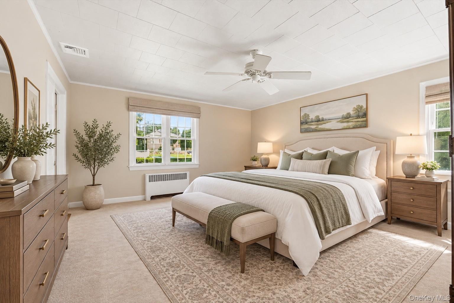 **Virtually Staged** Primary bedroom suite featuring a ceiling fan, dual nightstands with task lighting, wood-finish dresser with mirror, multiple win