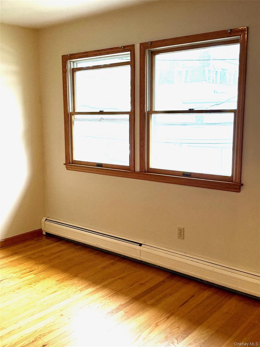 Spare room with a baseboard radiator and light wood-type flooring