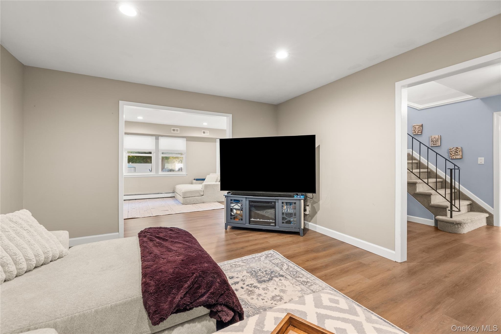 Living room. Recessed lighting illuminates the wood-finish flooring