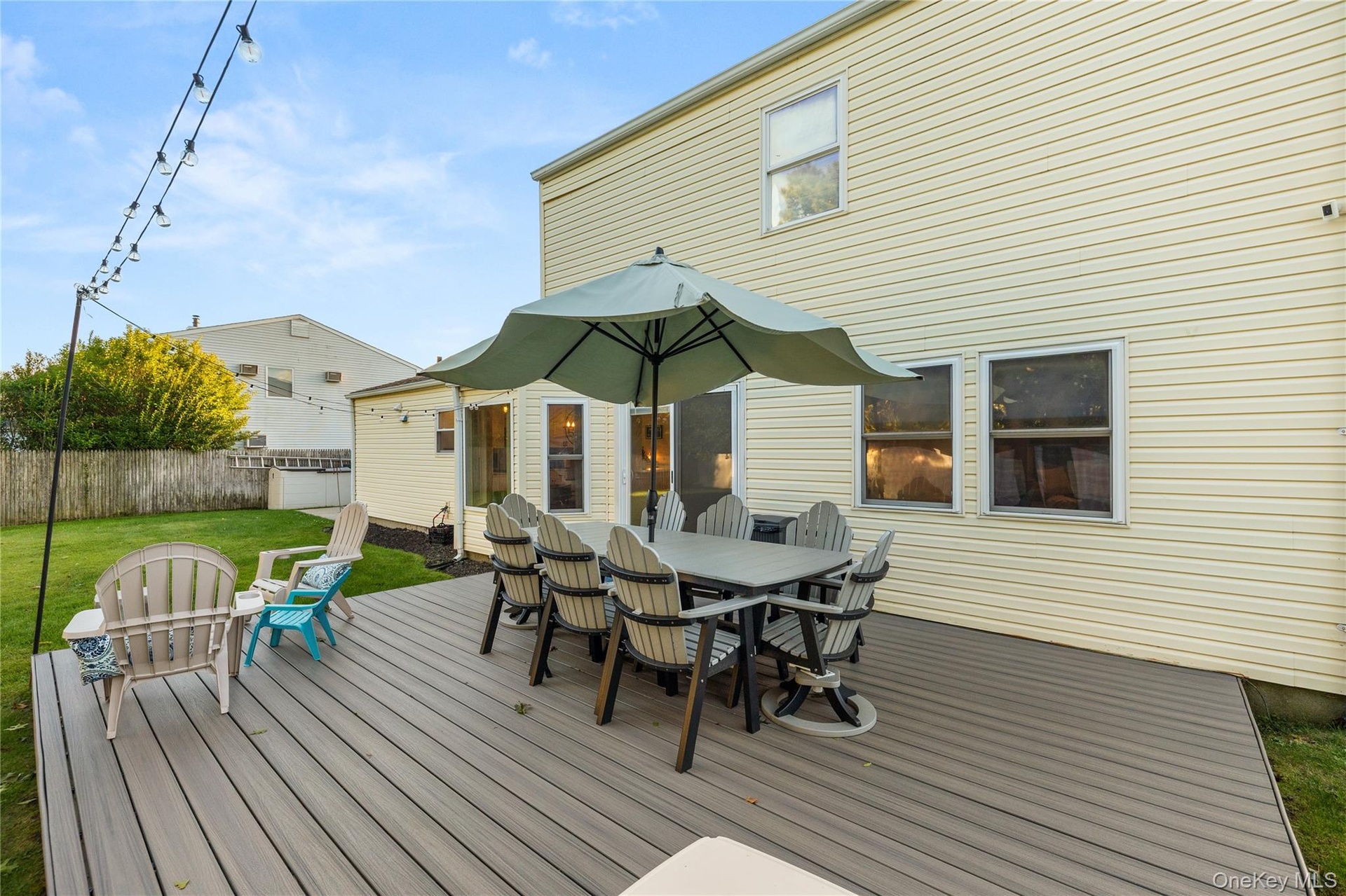Expansive Trex deck featuring integrated dining and lounge areas, anchored by a center umbrella for shade