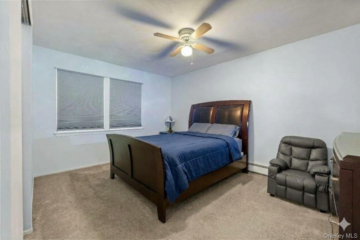 Recessed window with privacy blinds, ceiling fan with integrated lighting, and carpeted flooring. AI edited.