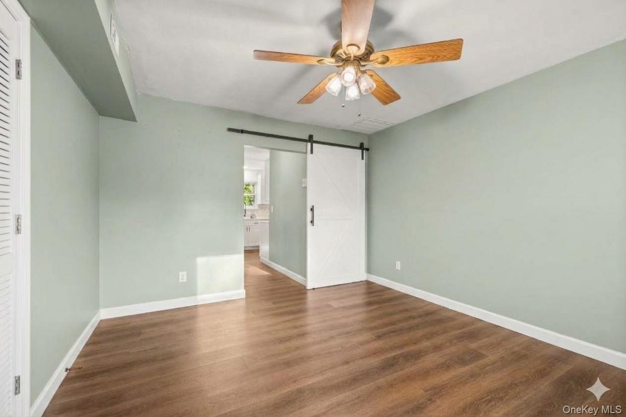 Bonus room on main level. Wood-finish flooring, ceiling fan with light fixture, sliding barn door. AI edited, all furniture removed.