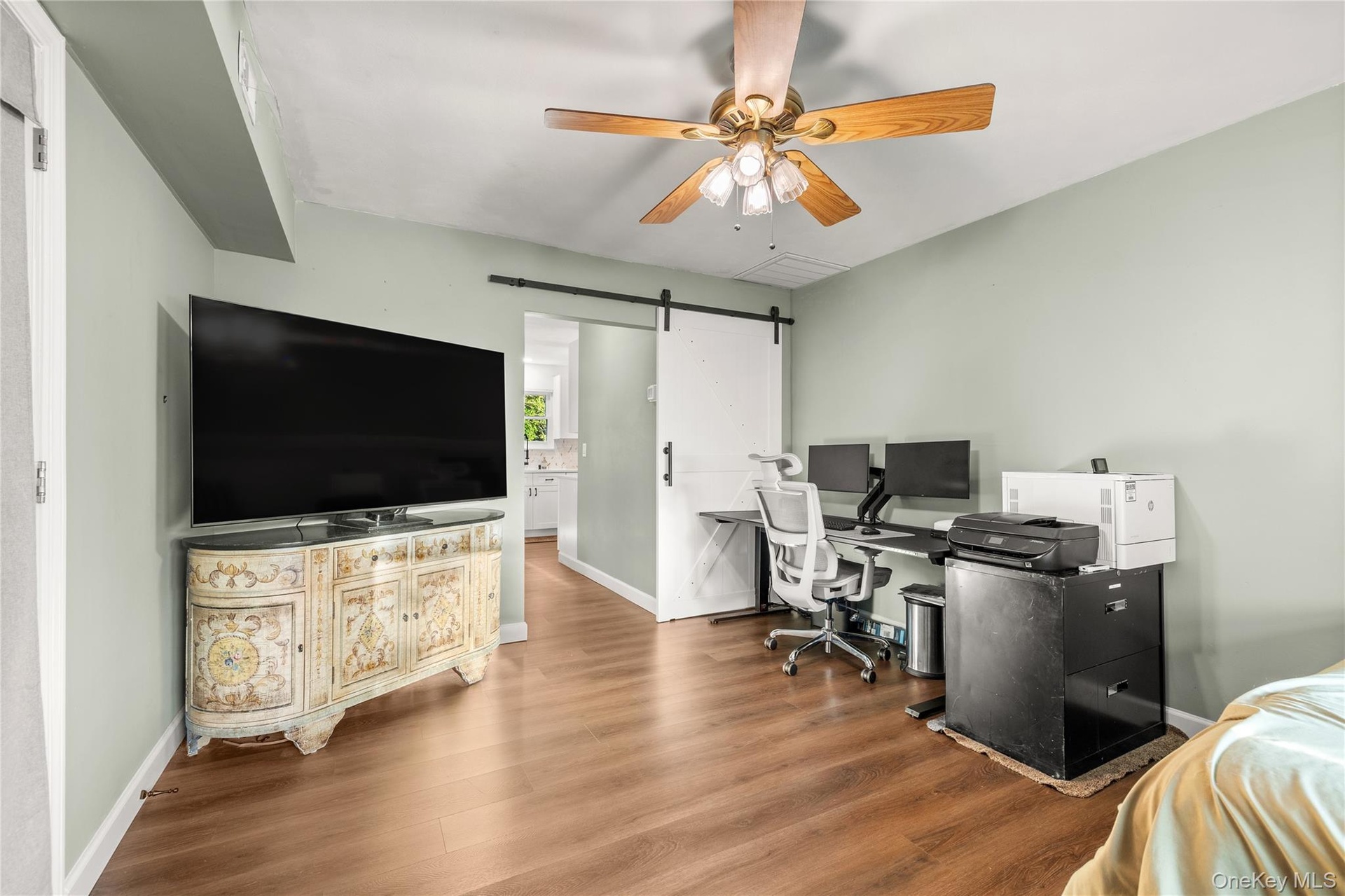 Bonus room on main level currently set up as an office space. Wood-finish flooring, ceiling fan with light fixture, and a white barn door