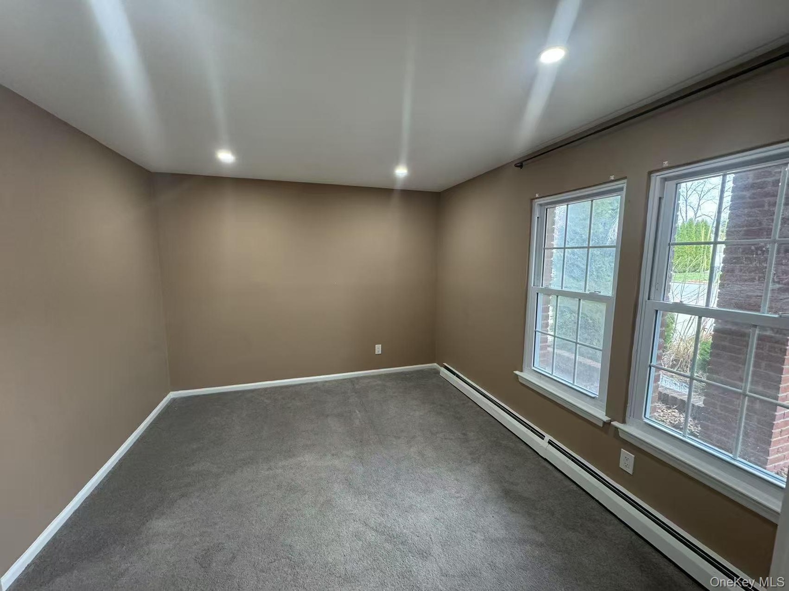 Carpeted spare room with baseboards, recessed lighting, and a baseboard radiator