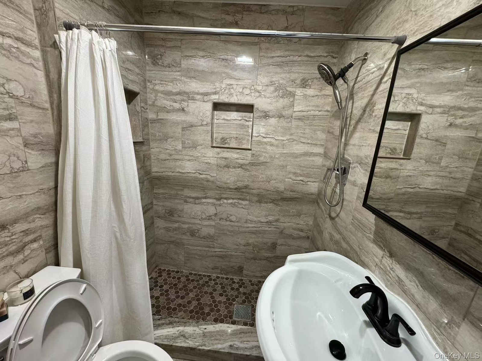 Bathroom featuring a sink, a stall shower, and toilet