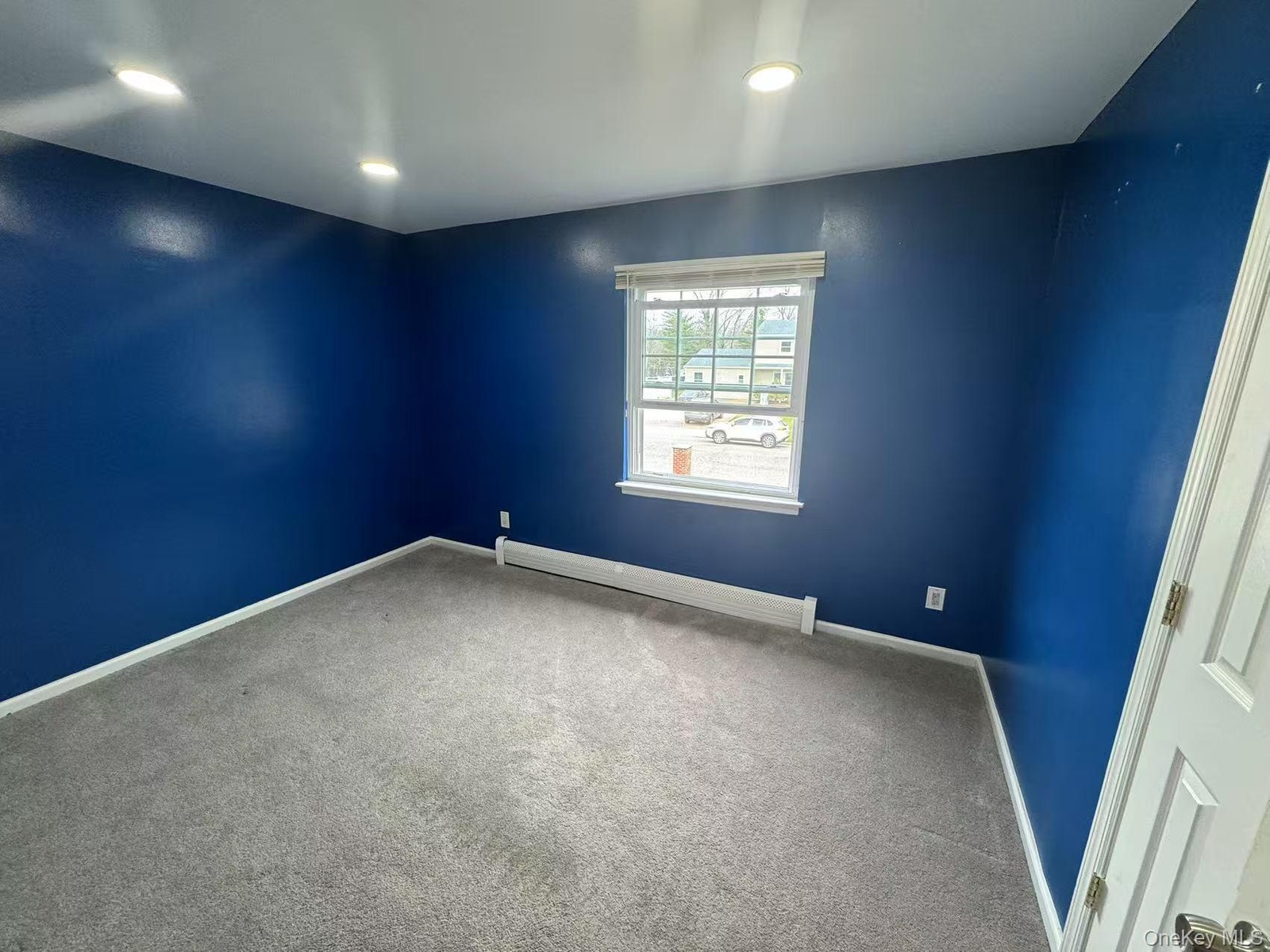 Carpeted spare room with baseboards, a baseboard heating unit, and recessed lighting