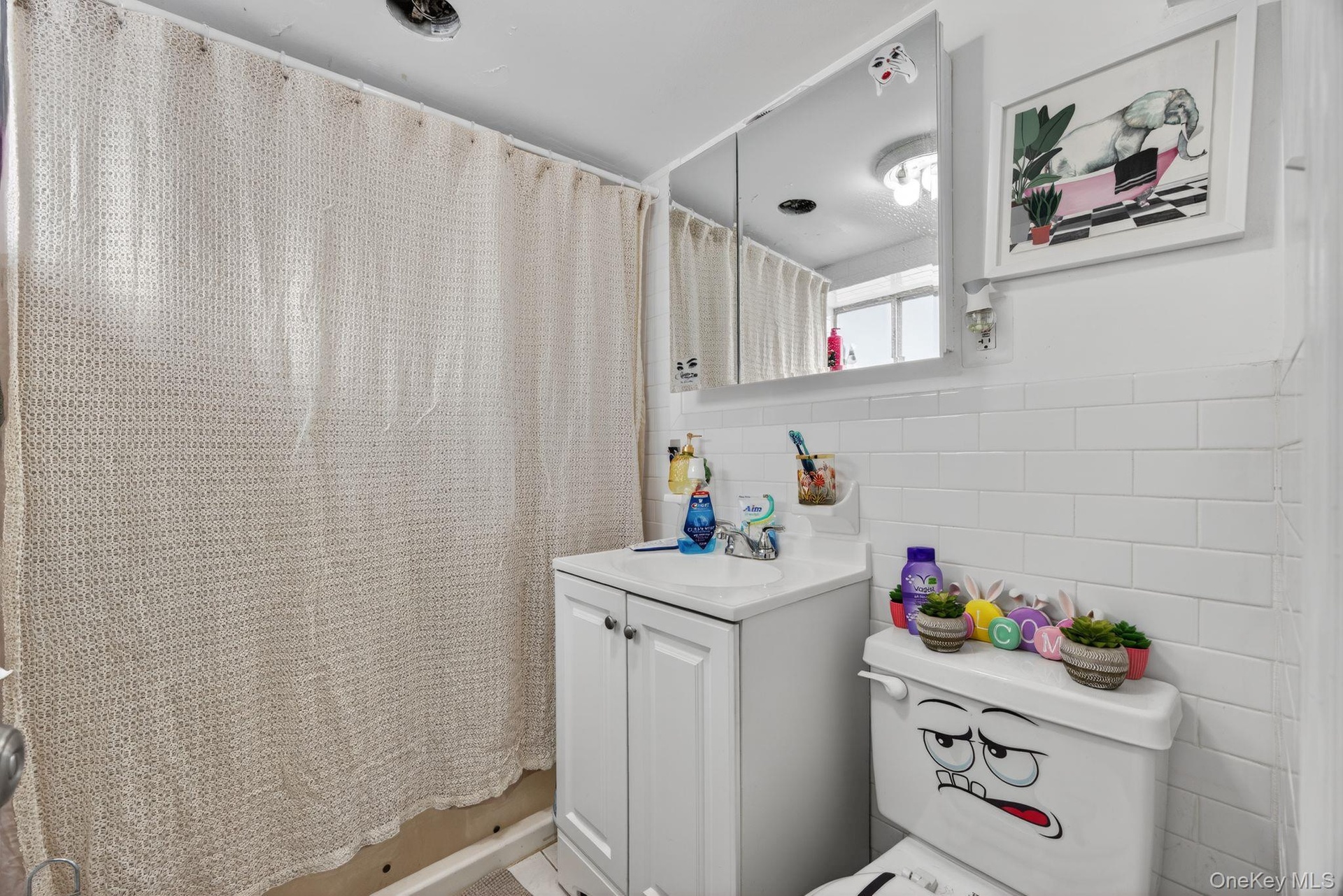 Bathroom featuring tile walls, curtained shower, vanity, and decorative backsplash