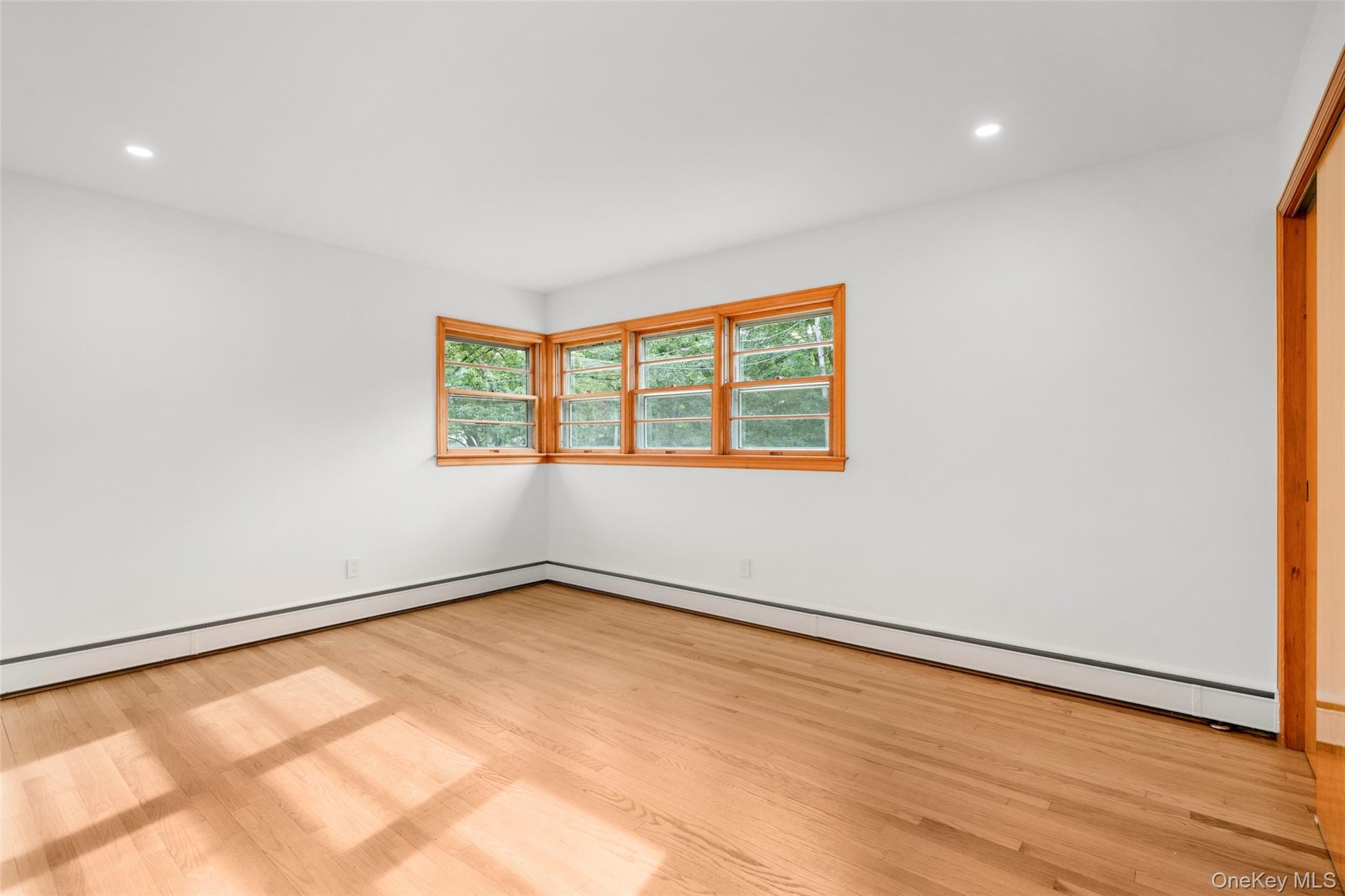 Mid-century corner window and pristine oak floors in primary bedroom
