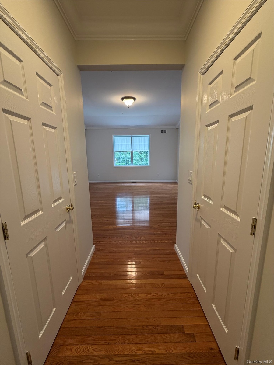 hallway with 2 walk-in closets for primary bdrm from bath