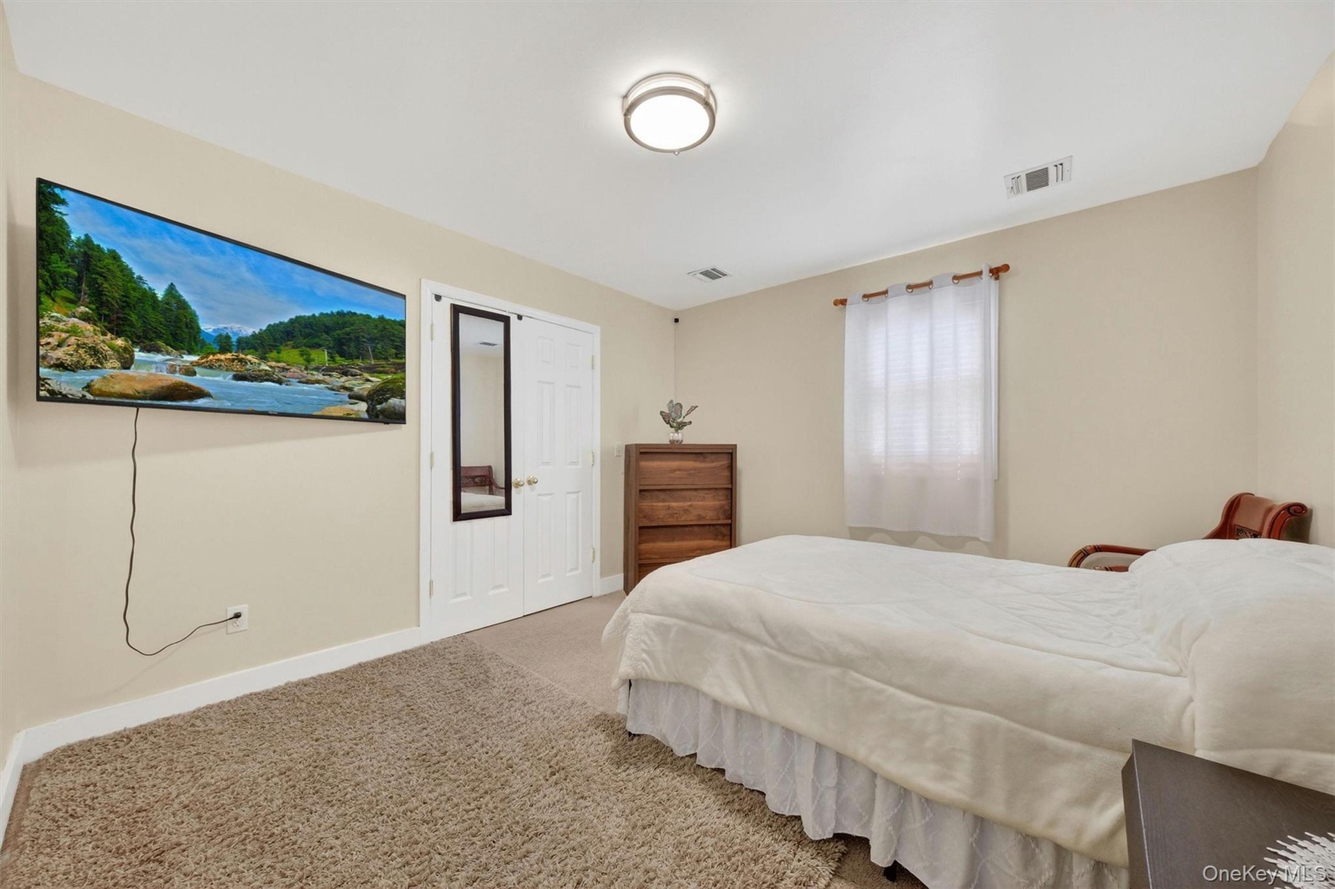 Neutral wall paint, carpet flooring, a window with blinds, and a ceiling-mounted light fixture