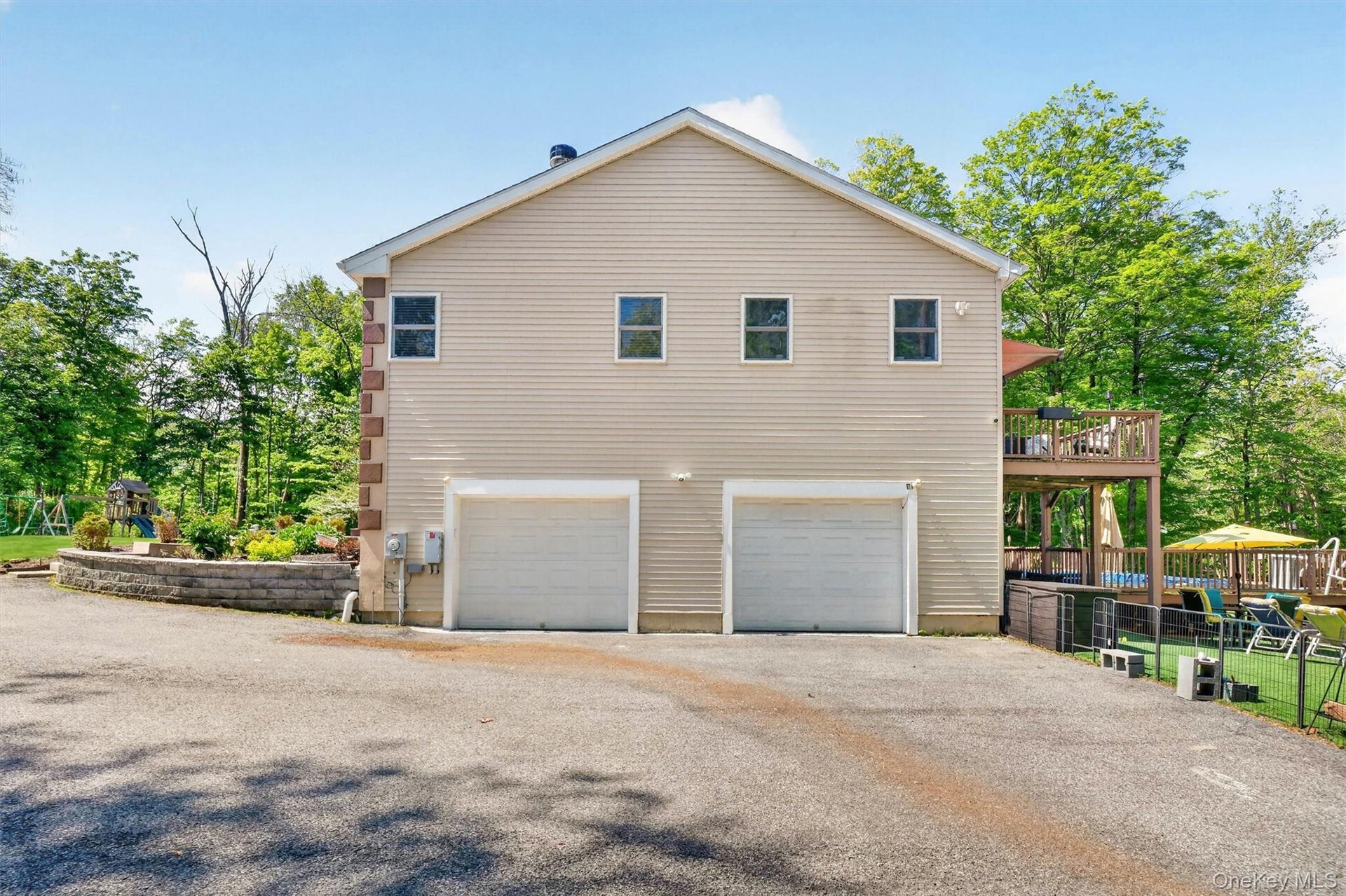 Two-car garage with light-colored siding, a stone accent column, and upper-level windows