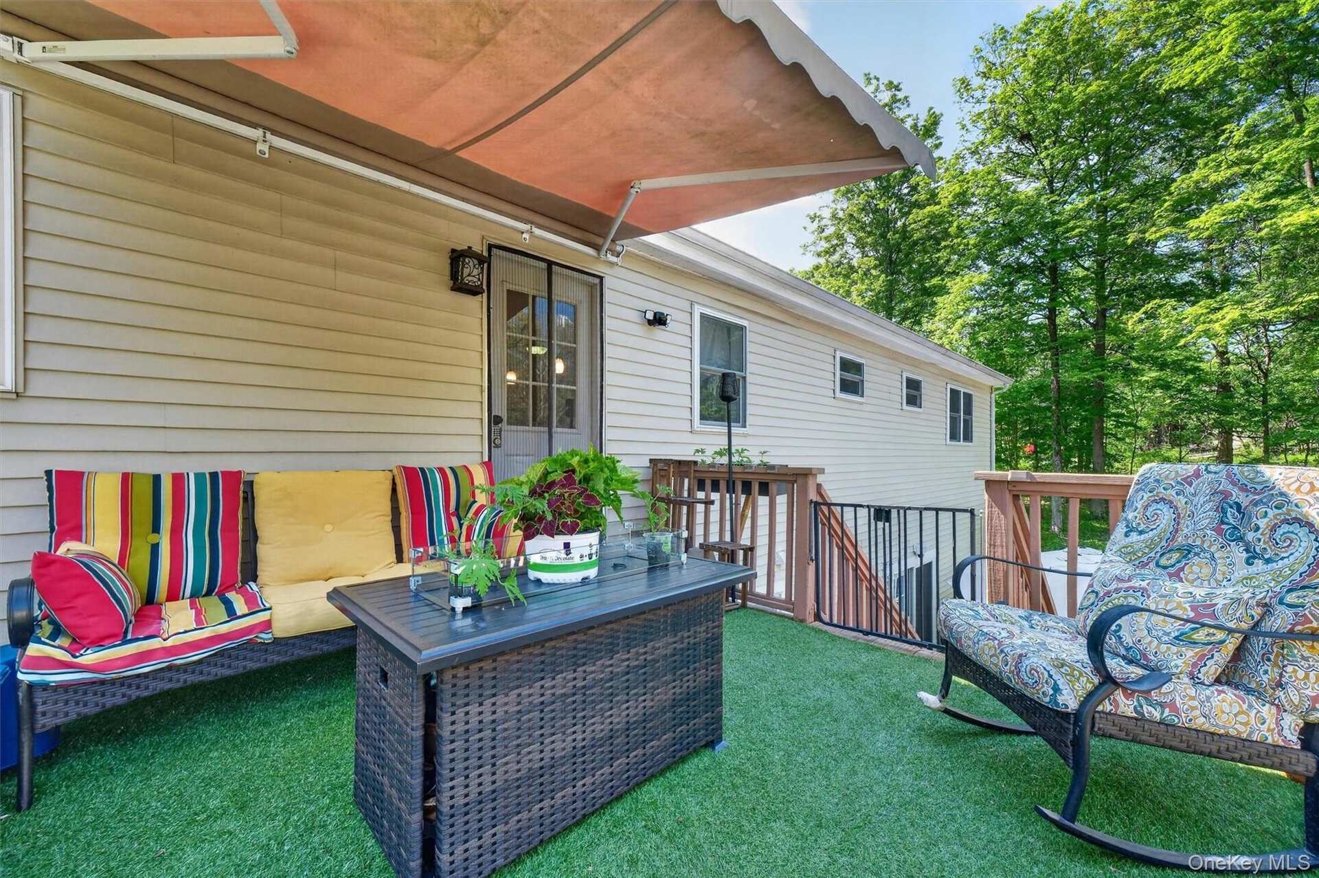 Deck with artificial turf surfacing, retractable awning, exterior door with glass inserts, and wood railing with metal balusters