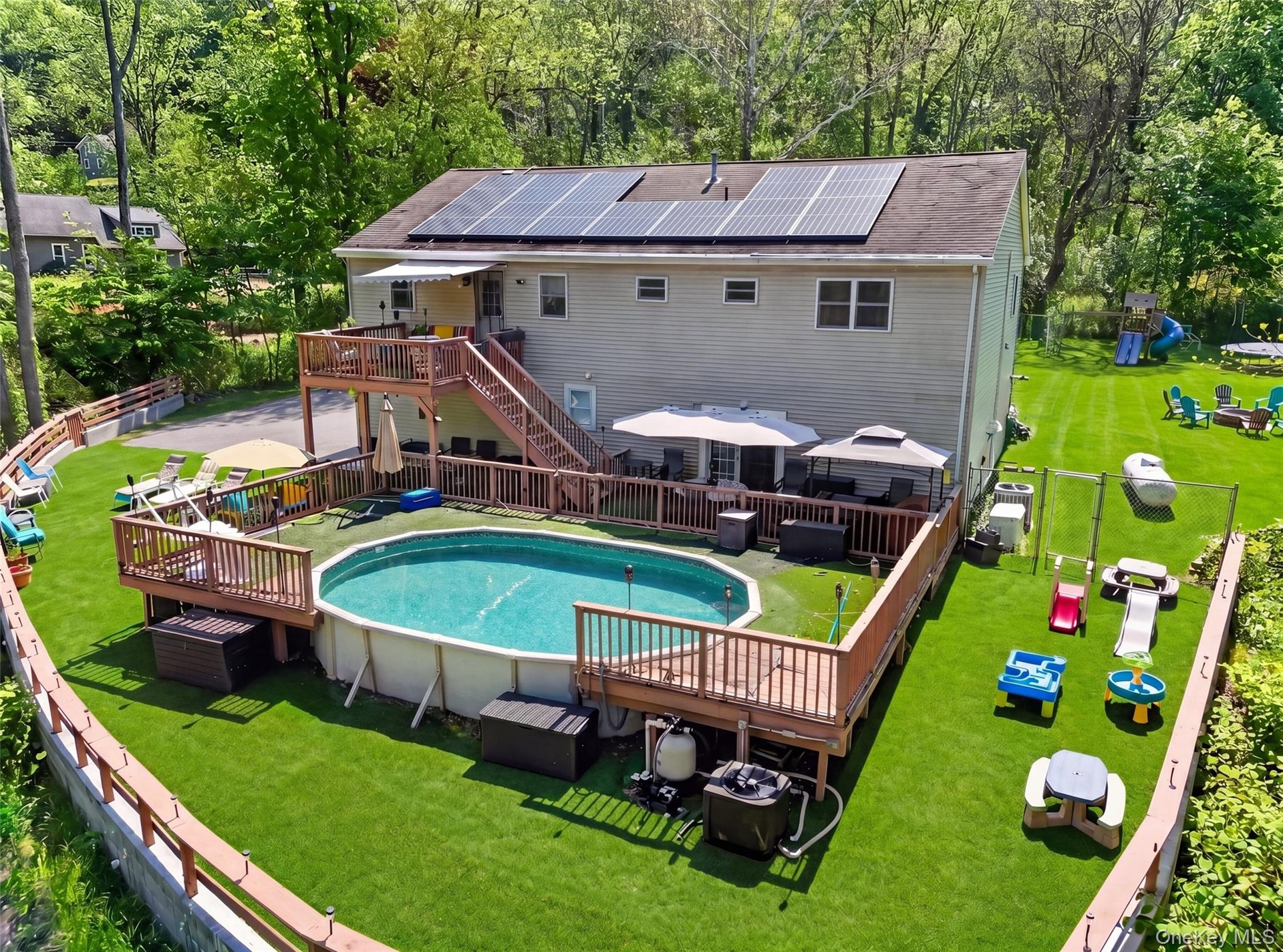 Rear exterior with solar panels, multi-level wood deck, and an above-ground pool