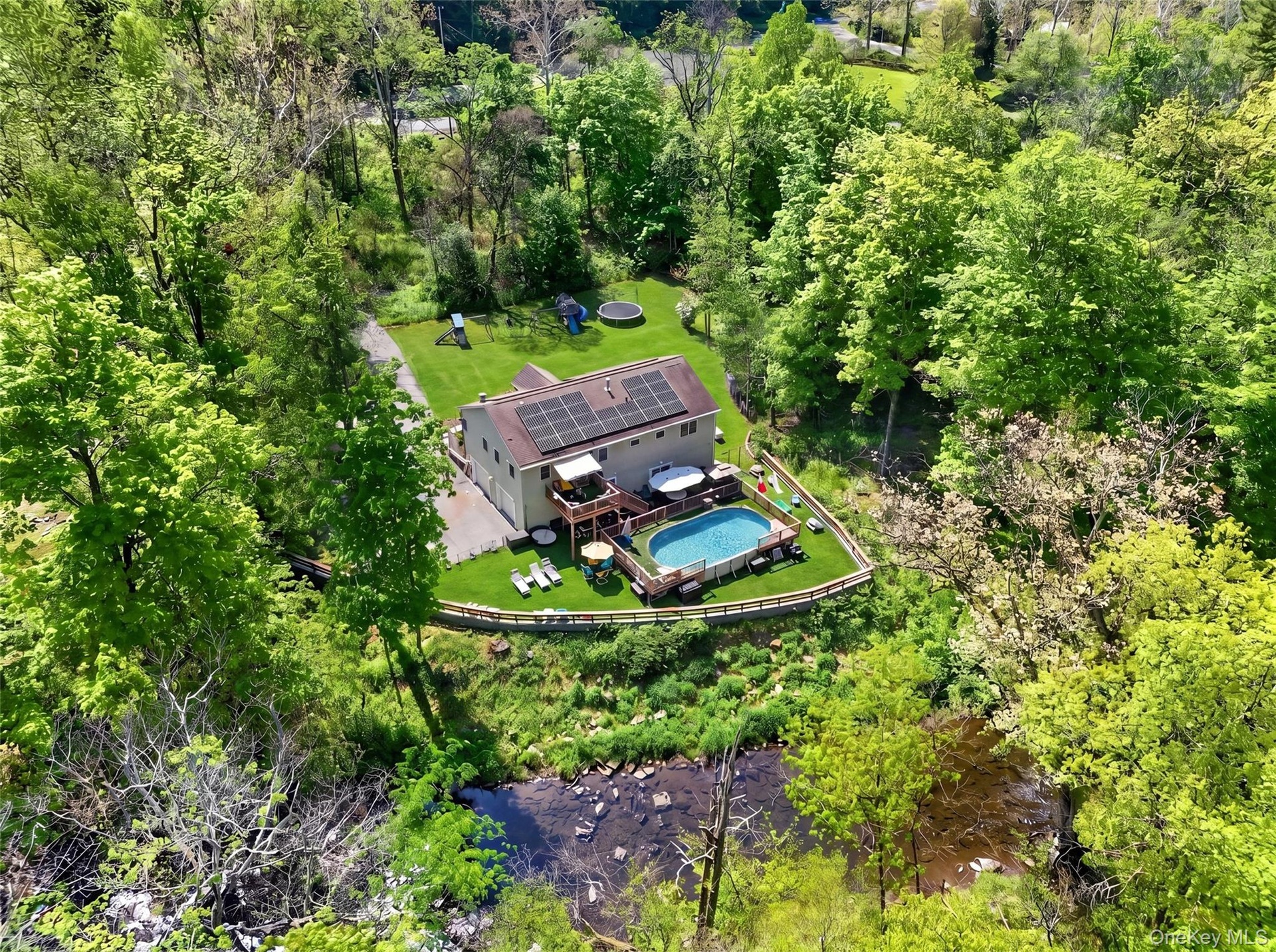 Two-story residence with solar panels, an above-ground pool with surrounding deck, and a multi-level wooden deck