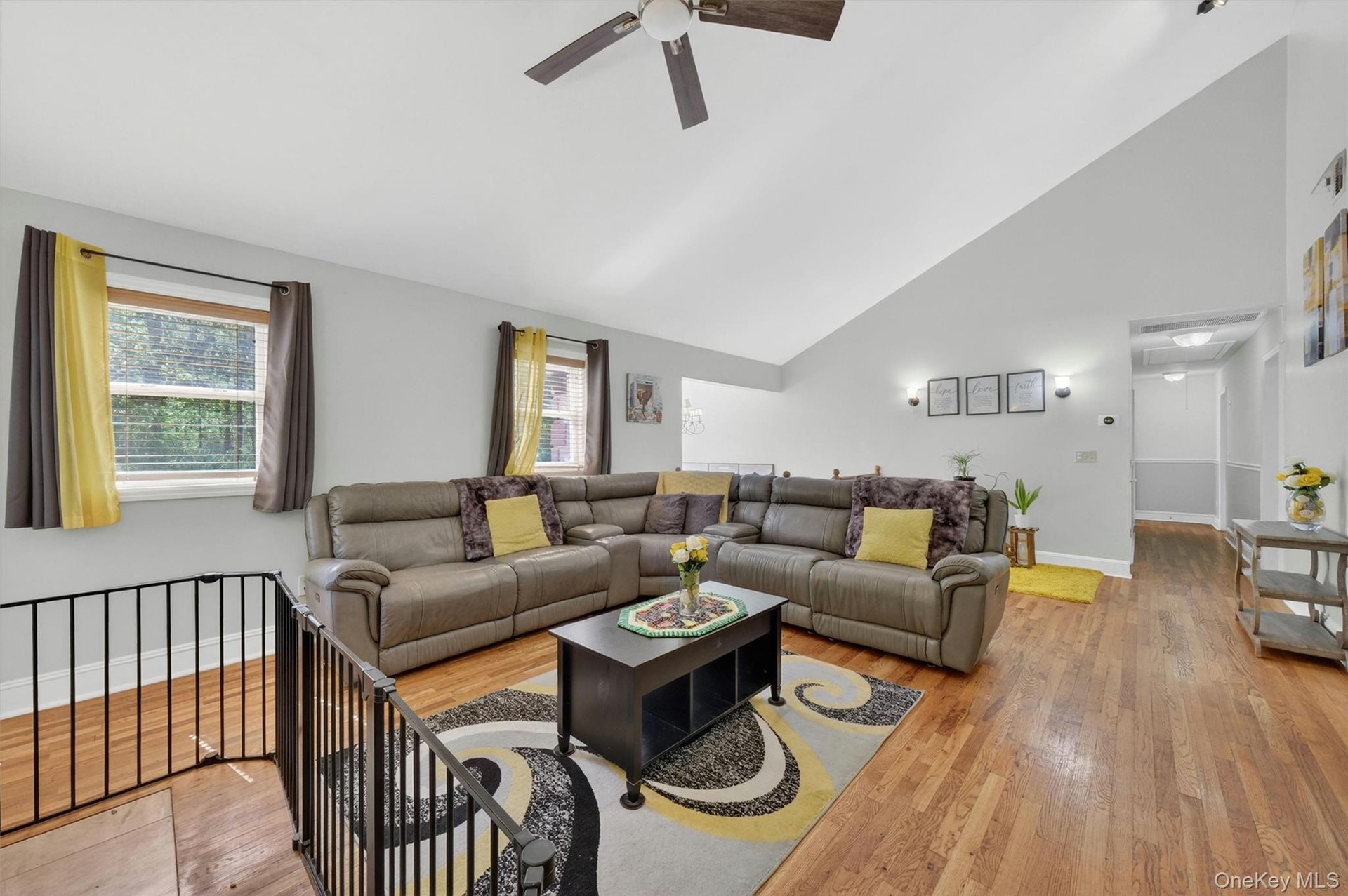 Vaulted ceiling, wood-finish flooring, ceiling fan, recessed lighting, and wall sconces