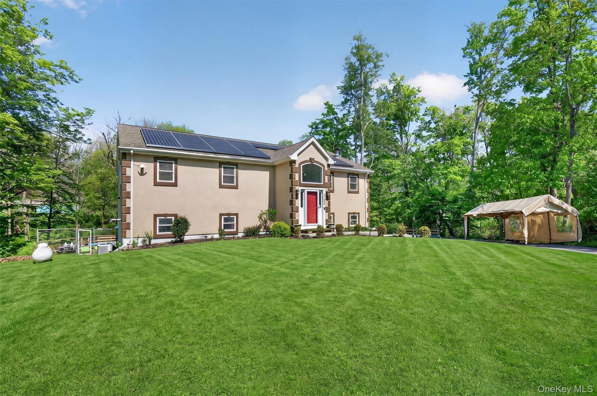 Stucco exterior with stone-look corner accents, solar panels, and a red entry door