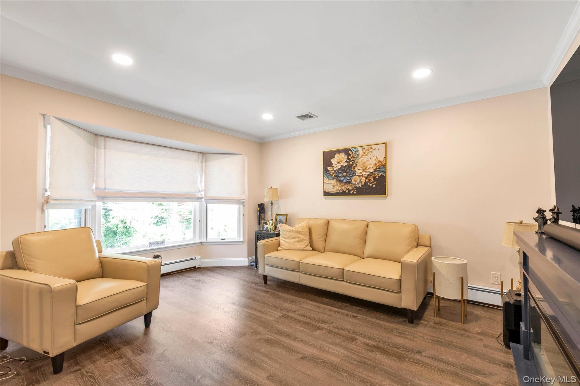 Bay window with multiple panels, wood-finish flooring, recessed ceiling lighting.