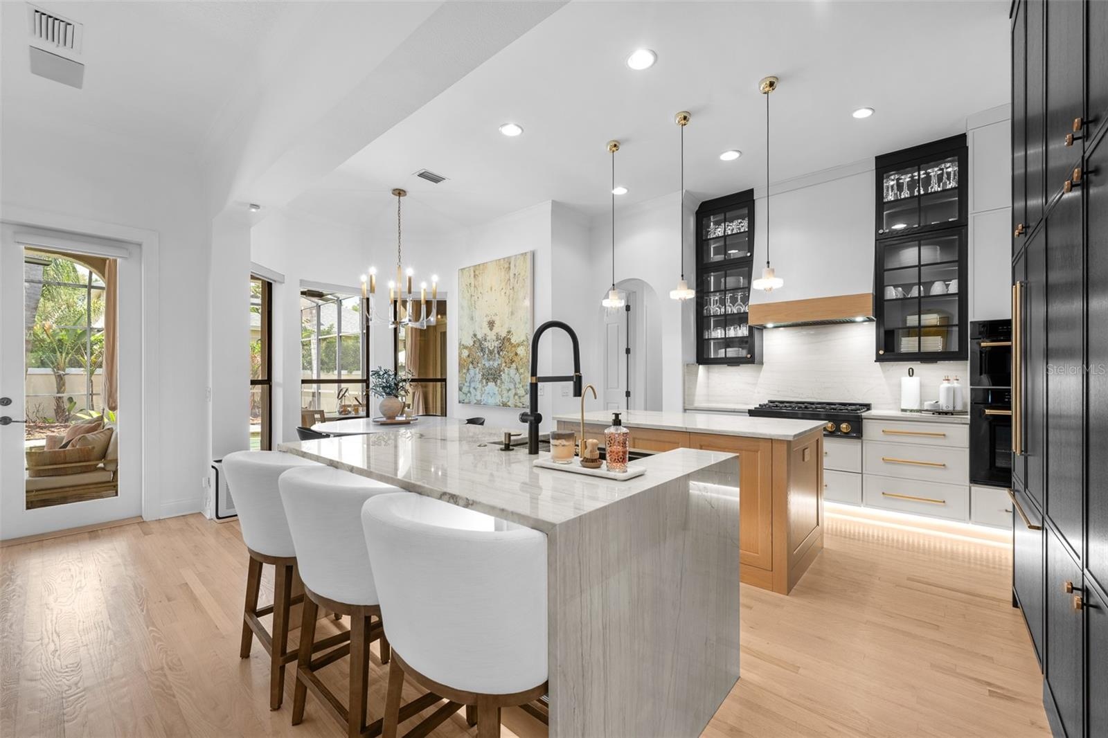 Island seating for four, matte black faucet, and under-cabinet lighting.