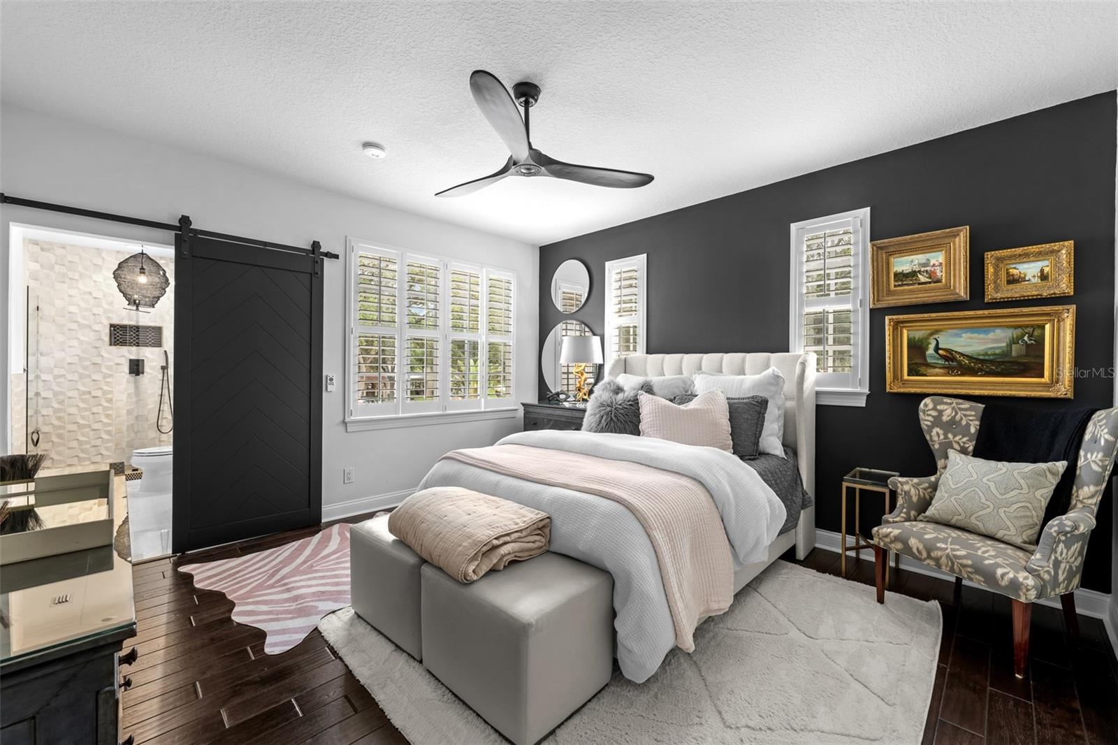 2nd Bedroom with dark accent wall, sliding barn door, ceiling fan, and plantation shutters.
