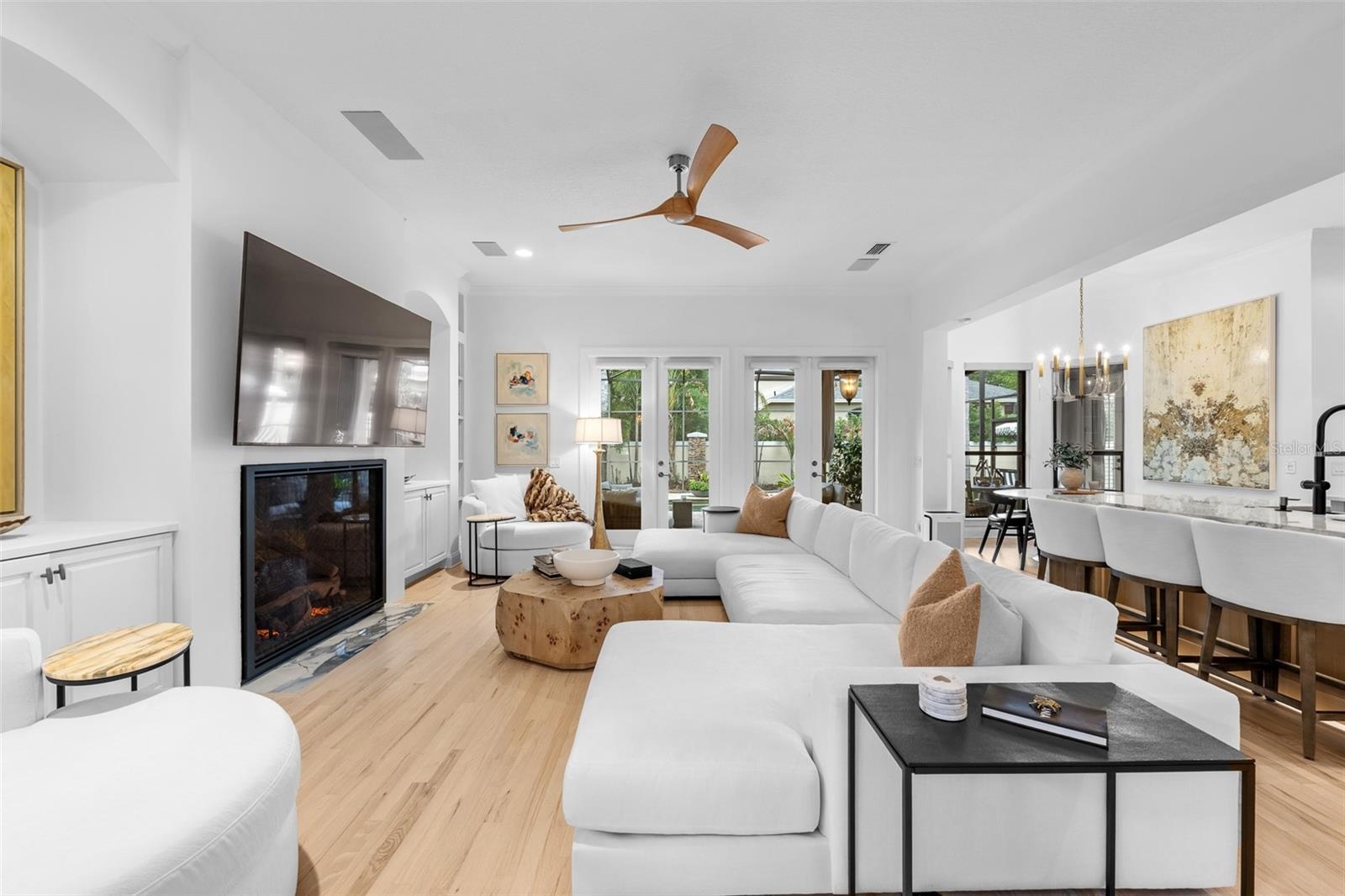 Fireplace with mounted TV above, built-in shelving, and French doors to the pool area.