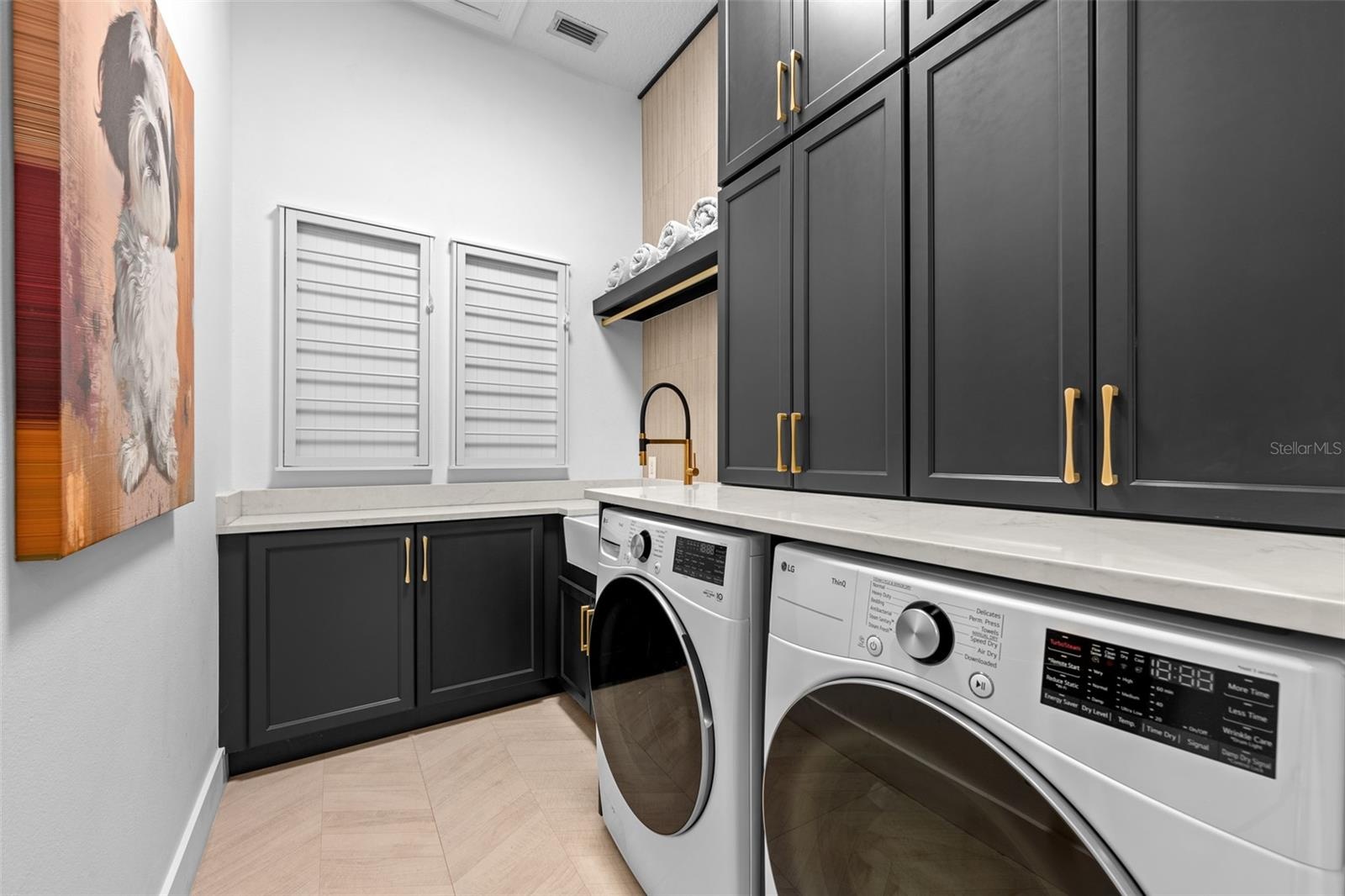 Laundry Room - Black shaker cabinets with brass pulls, front-load washer and dryer, and built-in louvered storage cabinets.