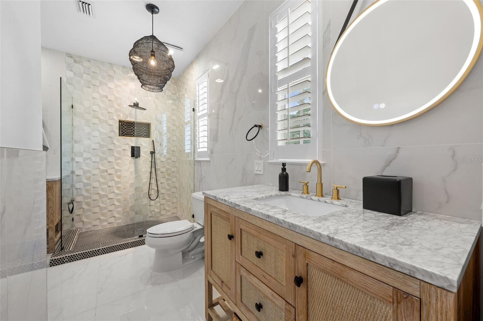 Second Bathroom (upstairs) - Walk-in shower with black fixtures, wood vanity with stone top, and brass-framed round mirror.