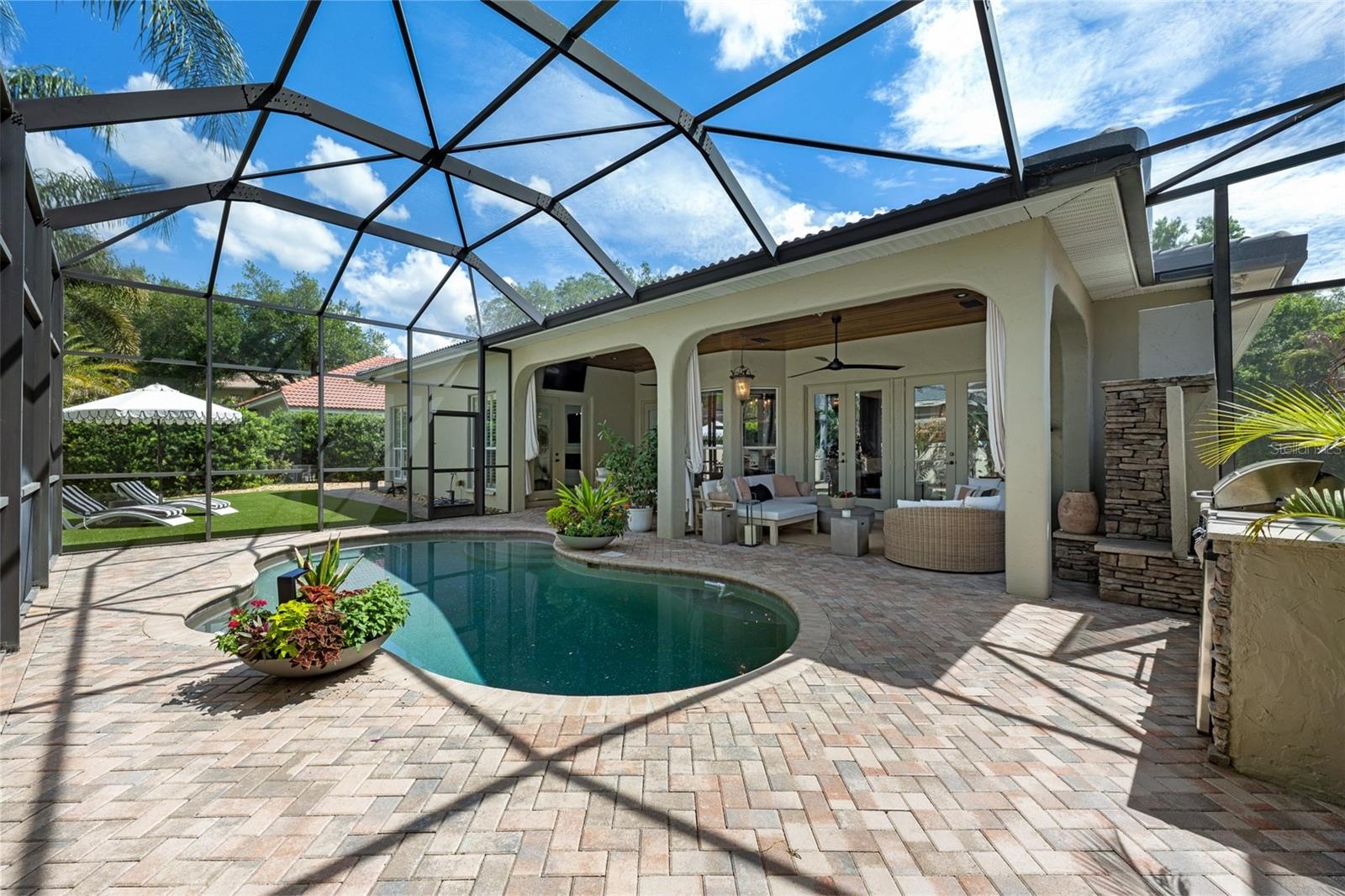 Screen-enclosed pool with brick paver deck and covered lanai.