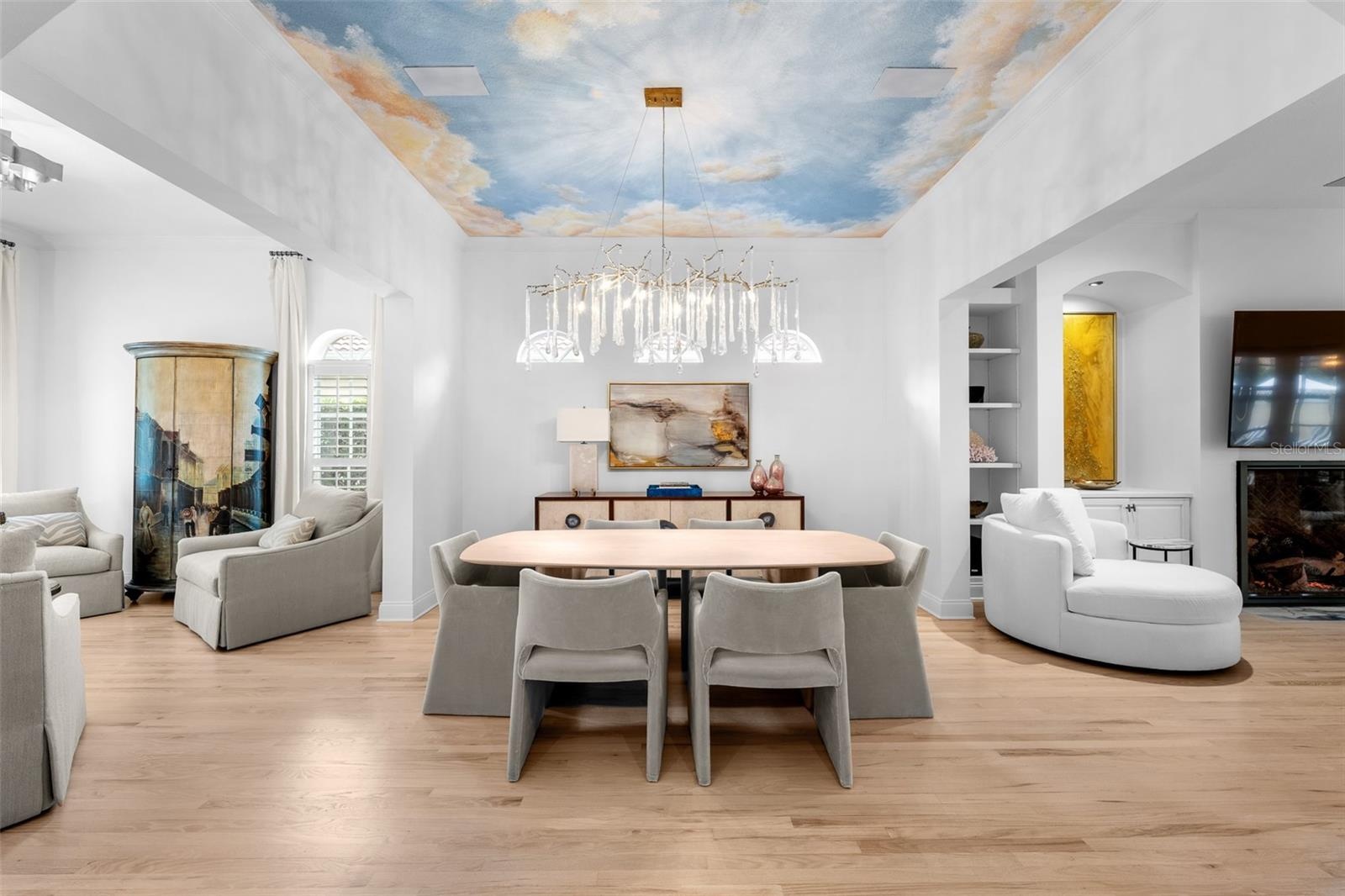 Sky ceiling mural, arched clerestory windows, and built-in cabinetry with open shelving.
