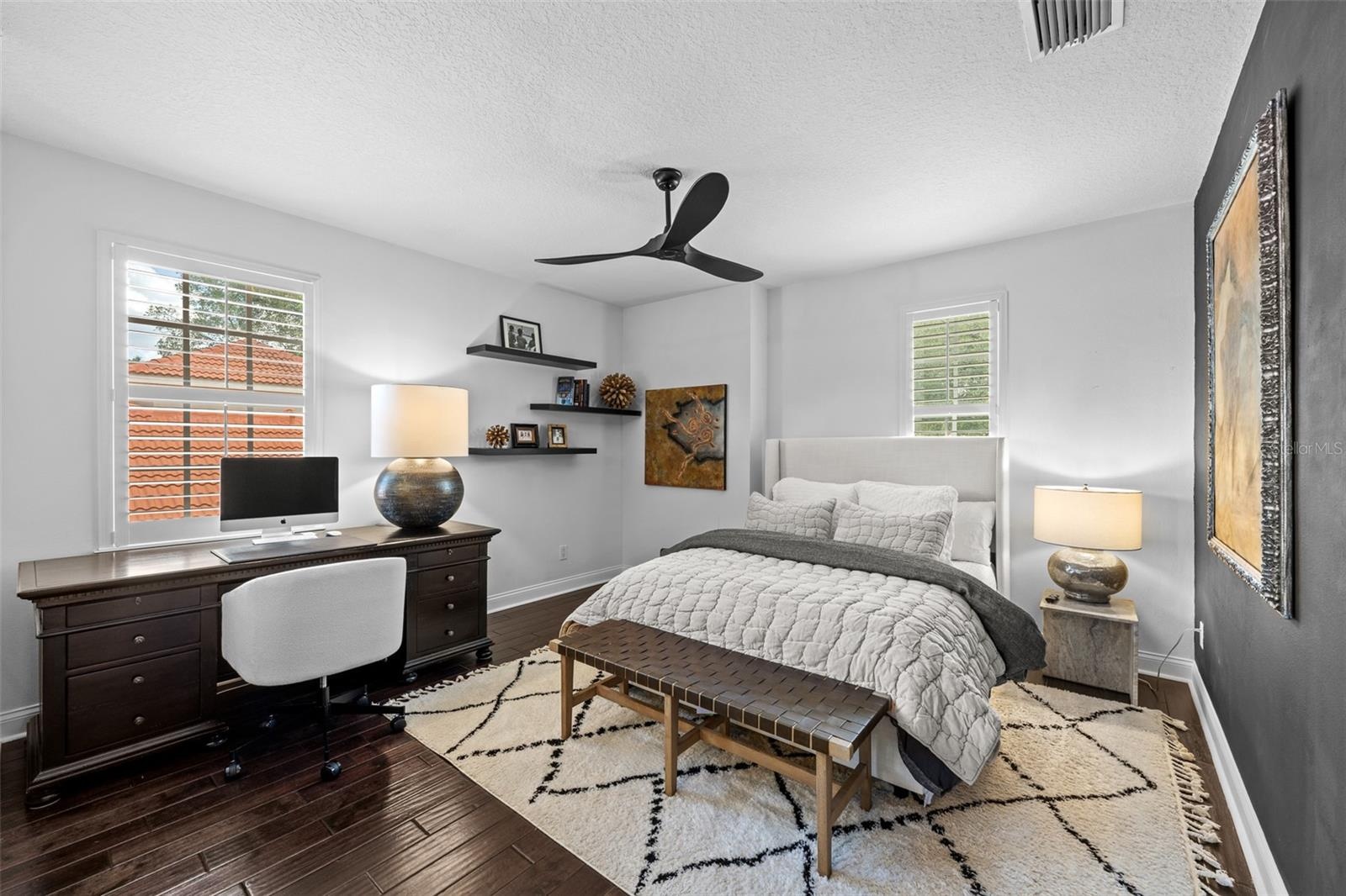 3rd Bedroom with desk area, floating wood shelves, and dark wood flooring.