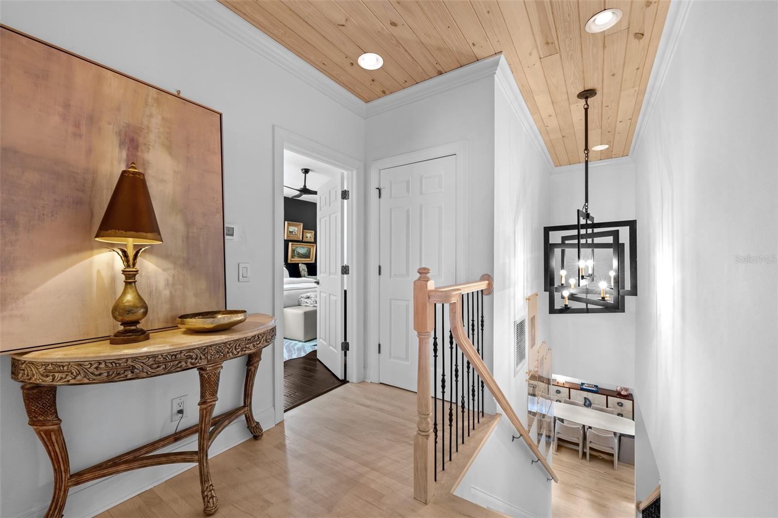 Upstairs landing — Vaulted wood plank ceiling, light wood flooring, and stair railing with lantern-style pendant.