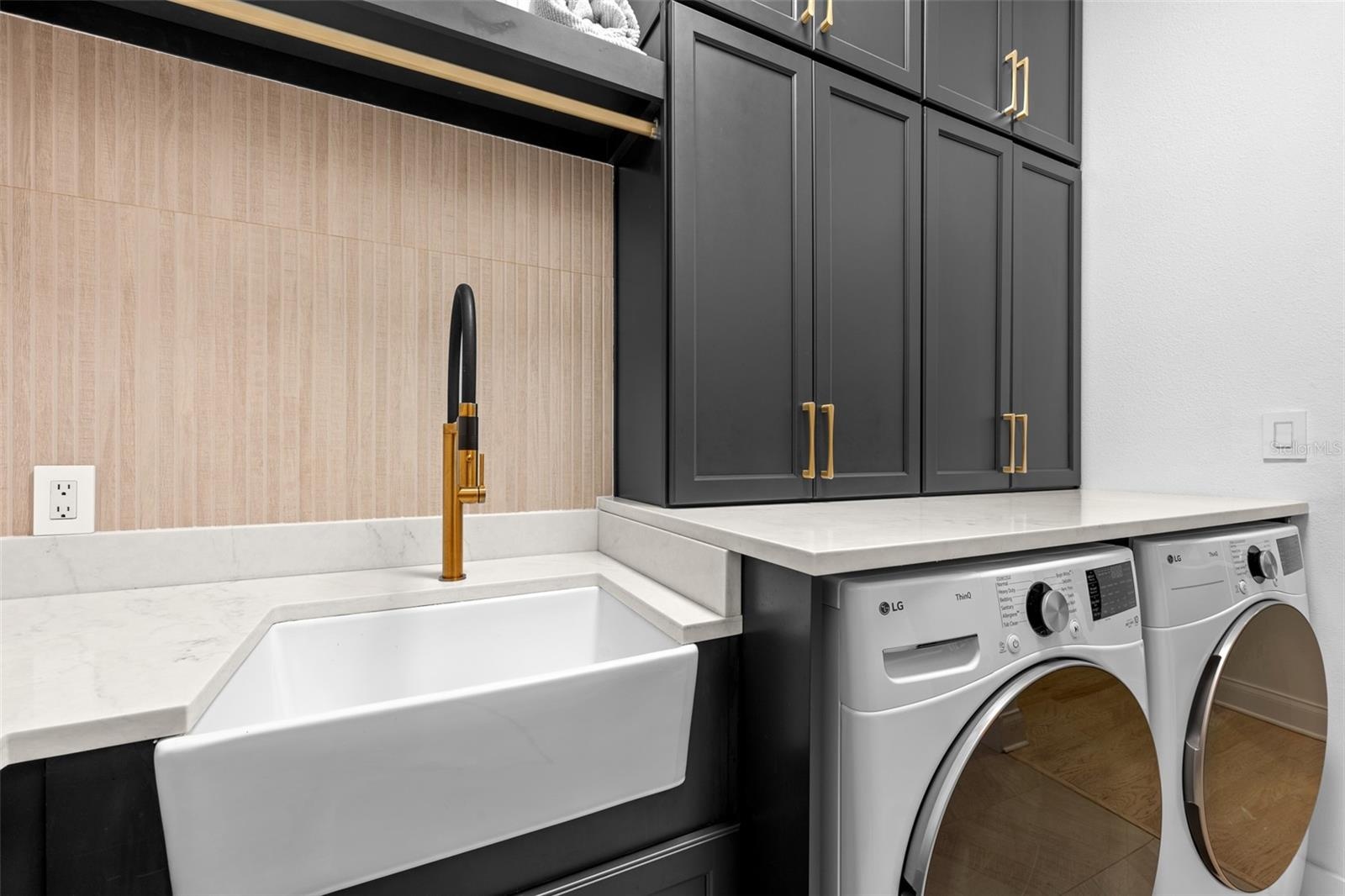 Laundry Room - Farmhouse utility sink with brass faucet, tile backsplash, and upper cabinet storage.