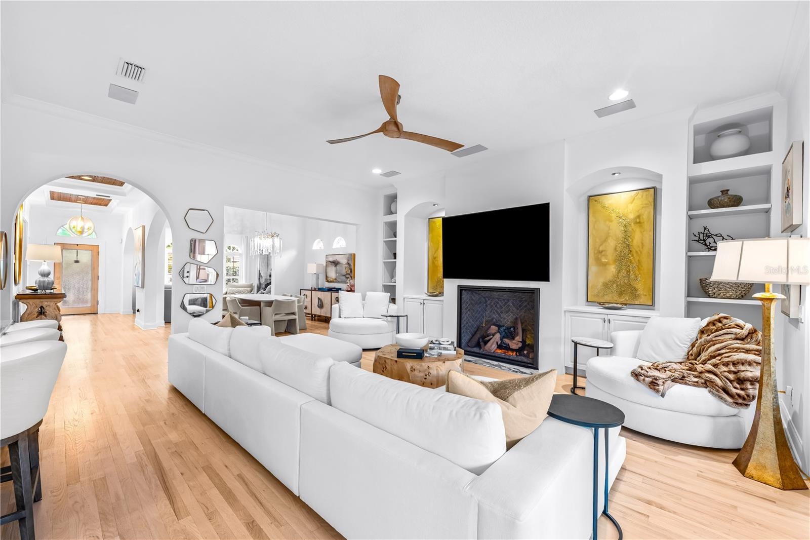 Fireplace with built-in shelving, ceiling fan, and French doors to the covered lanai.
