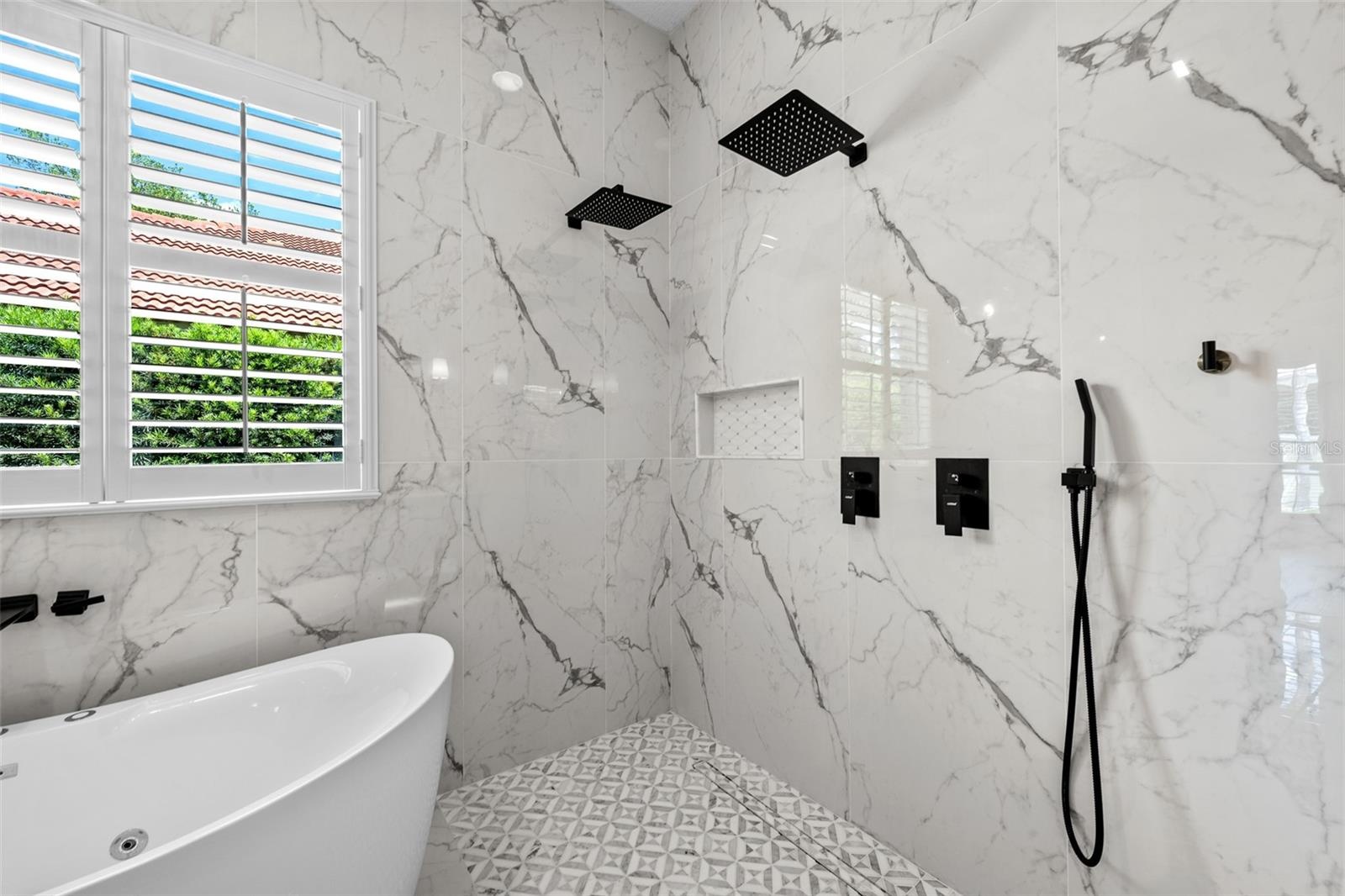 Dual black rain showerheads, wall niche, and marble-look wall tile.