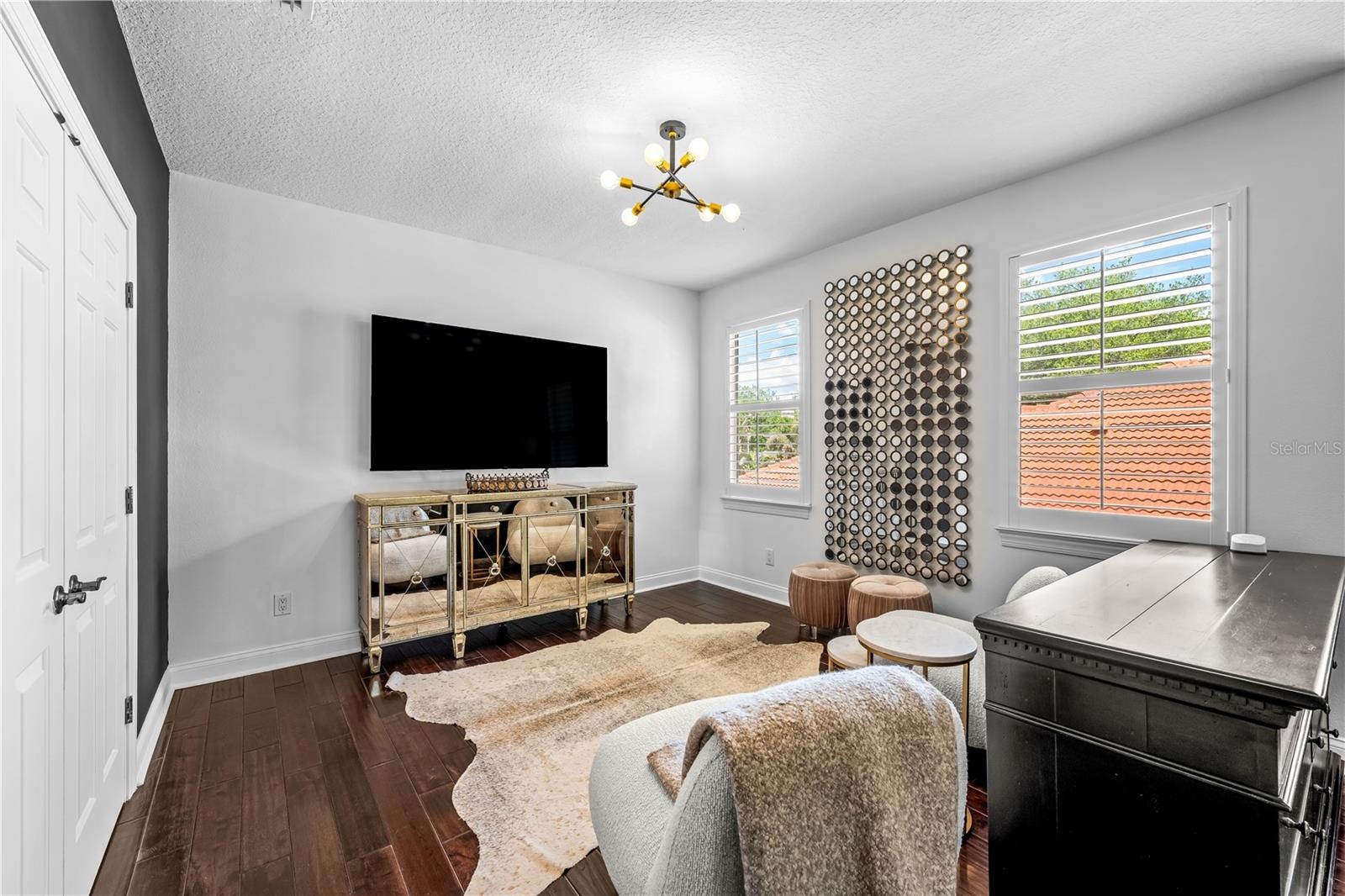 Sitting area with mounted TV and windows with plantation shutters.