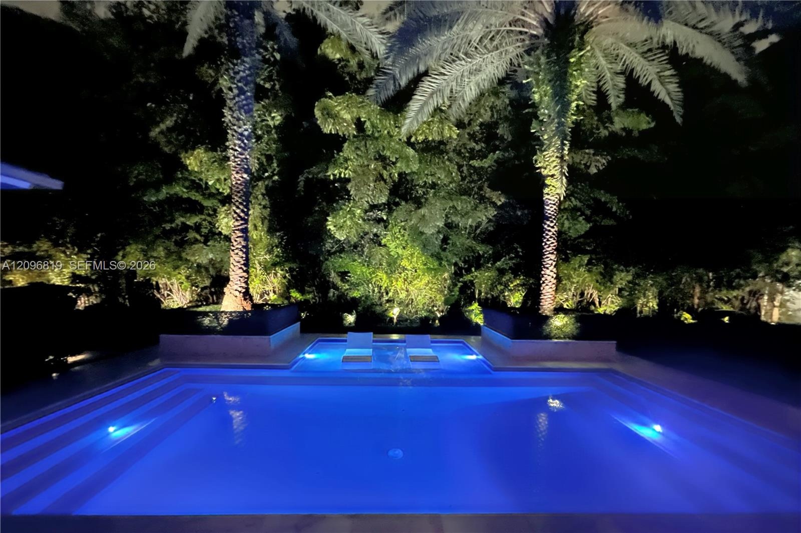 Resort Style Pool surrounded by lush tropical landscaping and dramatic evening lighting