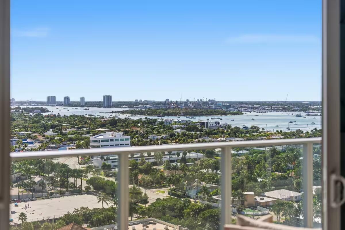 Expansive waterway and city skyline scenery from a high-rise balcony with glass railings