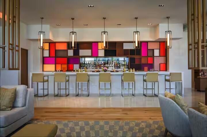 Integrated bar area with white countertop, colorful geometric paneling, and multiple pendant light fixtures