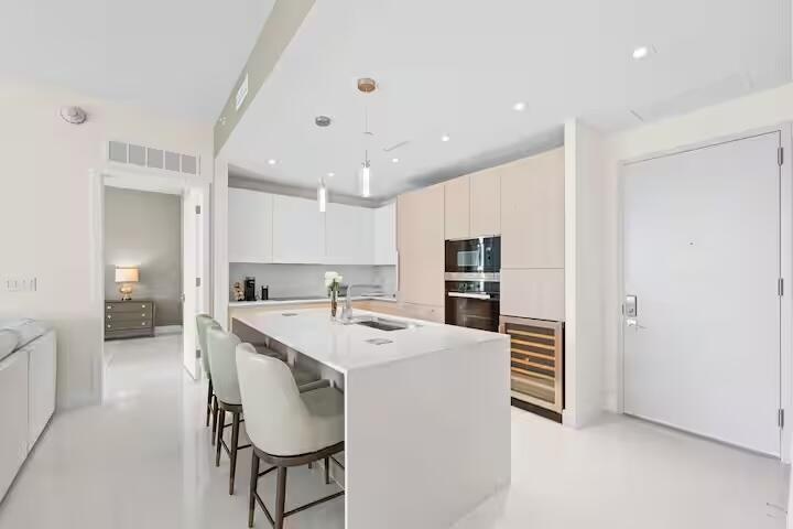 Sleek kitchen with a waterfall island, integrated stainless steel appliances, and a built-in wine cooler