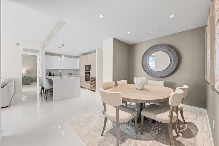 Open-concept living space featuring a dining area, recessed lighting, and white tile flooring