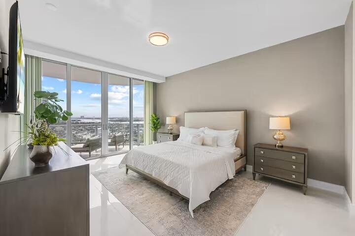 Floor-to-ceiling sliding glass doors, white tile flooring, recessed ceiling lighting, and a neutral wall color