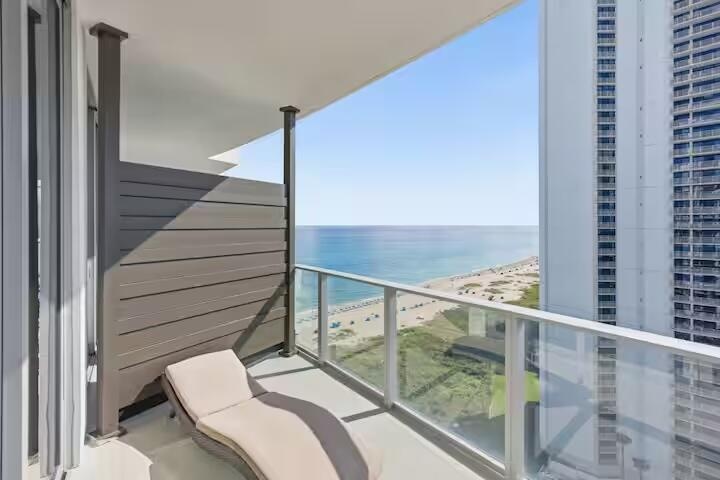 Private balcony with a glass railing, offering expansive ocean and coastline scenery