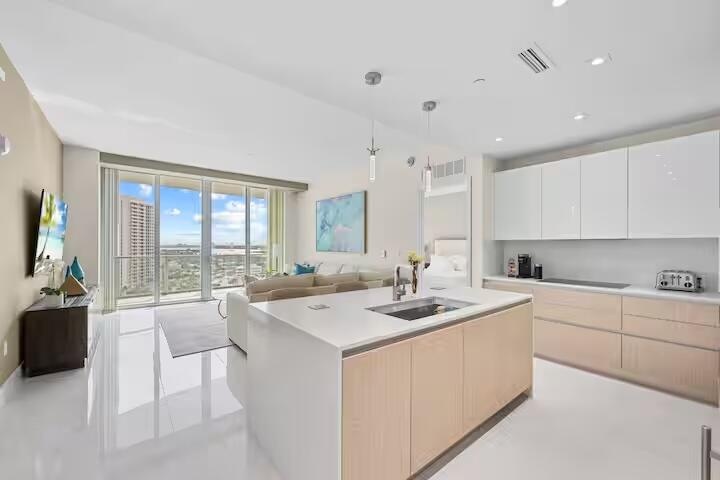 Open-concept living area with high ceilings, floor-to-ceiling windows, and white tile flooring