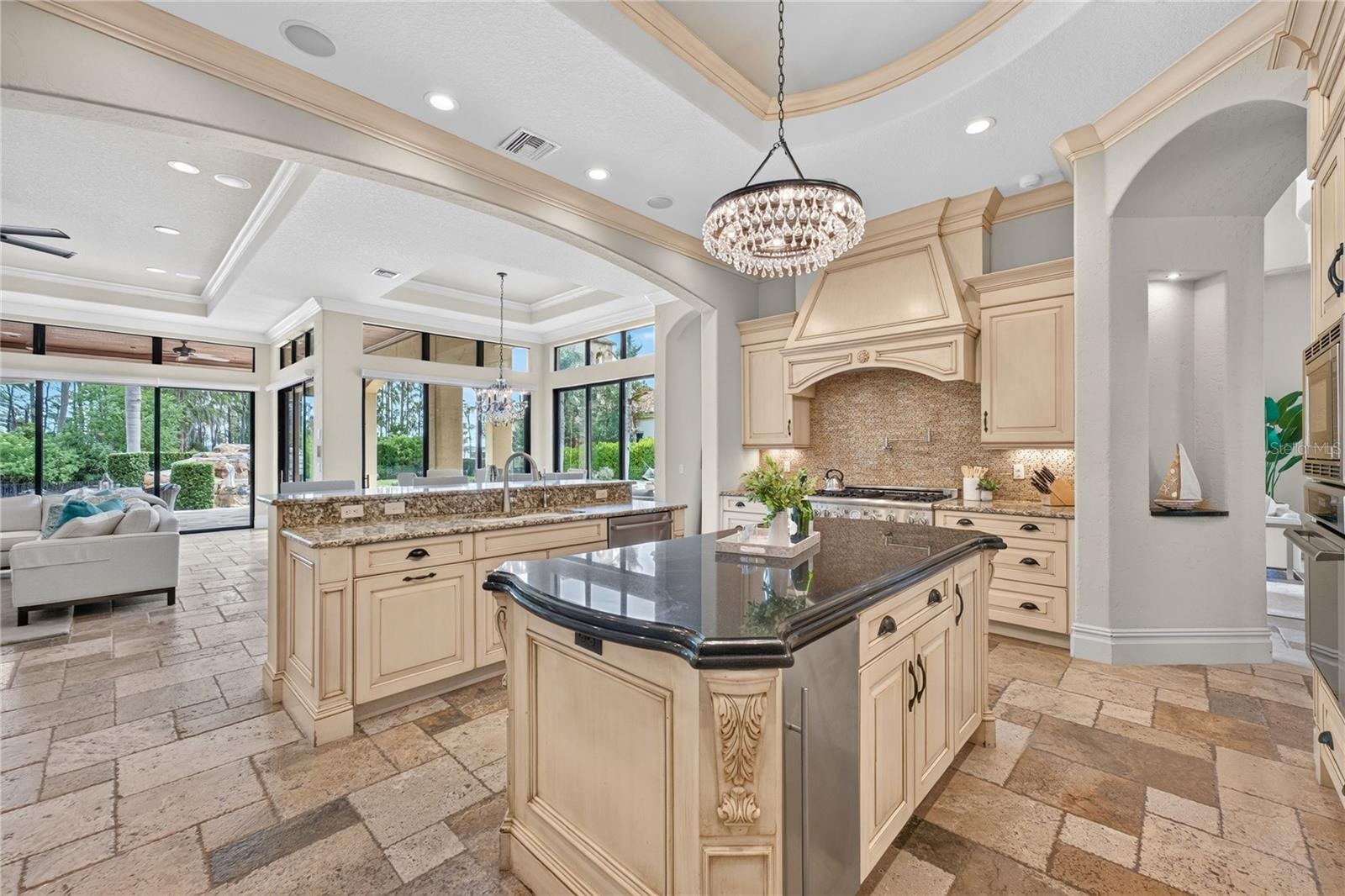 An open concept layout with casual living just beyond the kitchen. 5 sets of wall to wall sliders along the back of the home offer amazing views to th