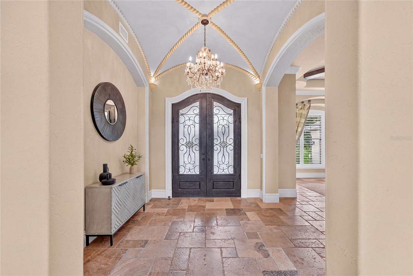 Iron and glass clad Double Door entry, barrel style ceiling with rope detail molding and chandelier bring this foyer to the next level.
